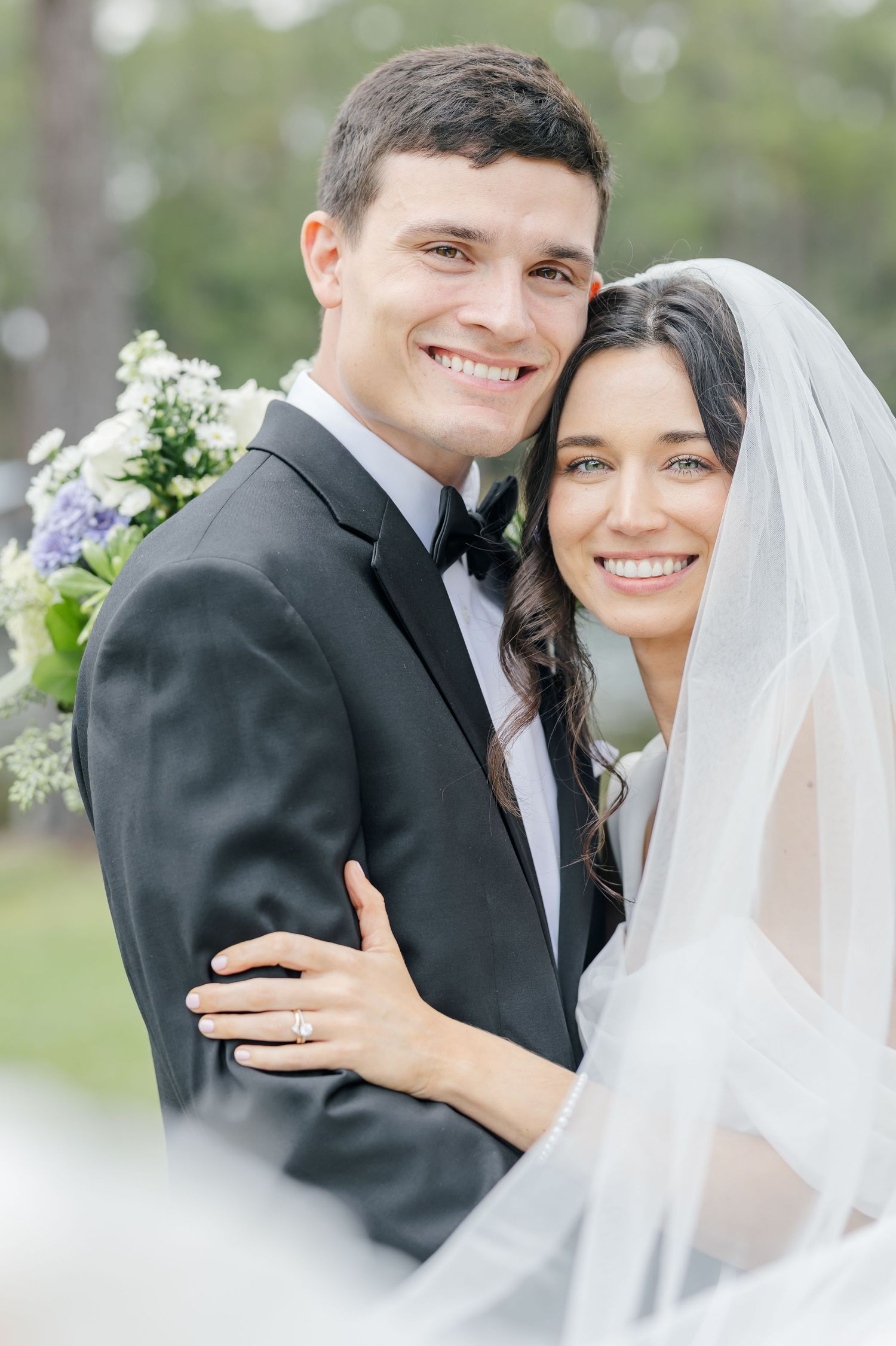Newlyweds embrace and smile during their wedding portraits in a serene garden setting.