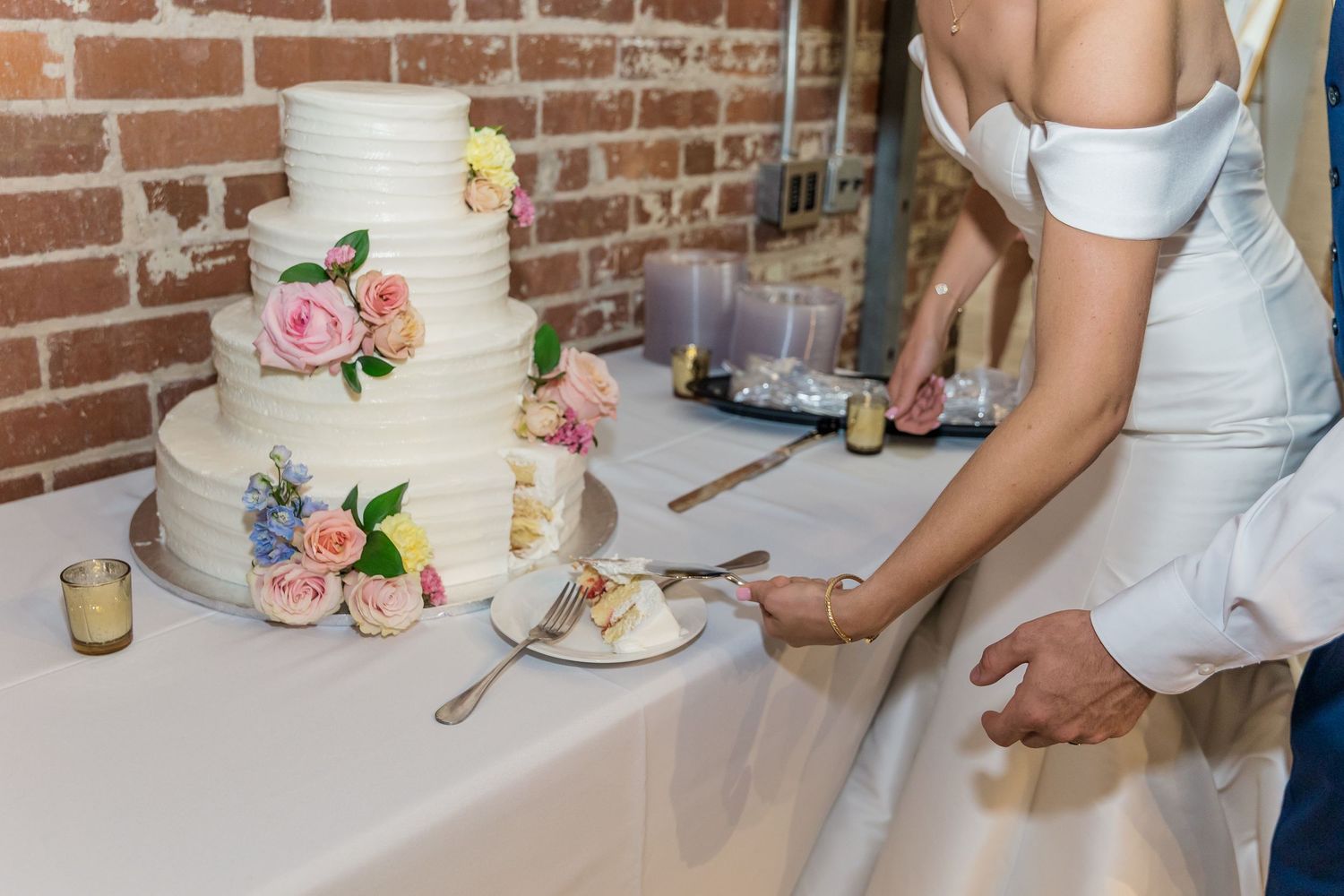 Wedding cake cutting sequence showing multiple angles of the traditional moment against exposed brick wall.