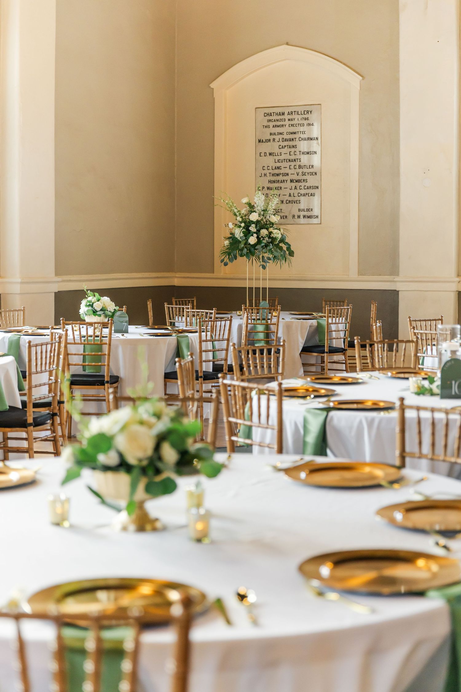 Elegant wedding reception venue with wooden chairs and white tablecloths set for a formal dining event.