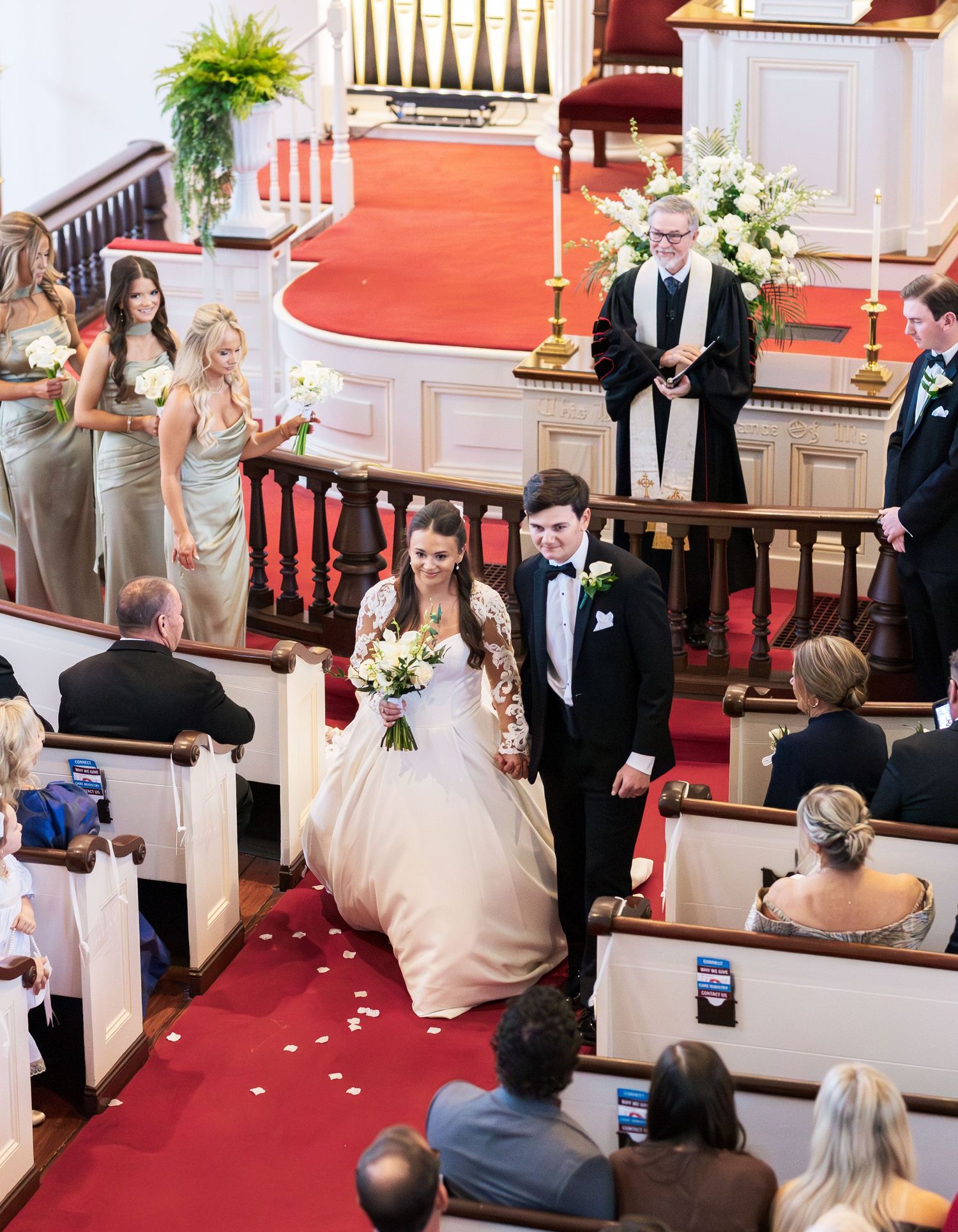 Newlyweds walking back down church aisle after wedding ceremony with rose petals.