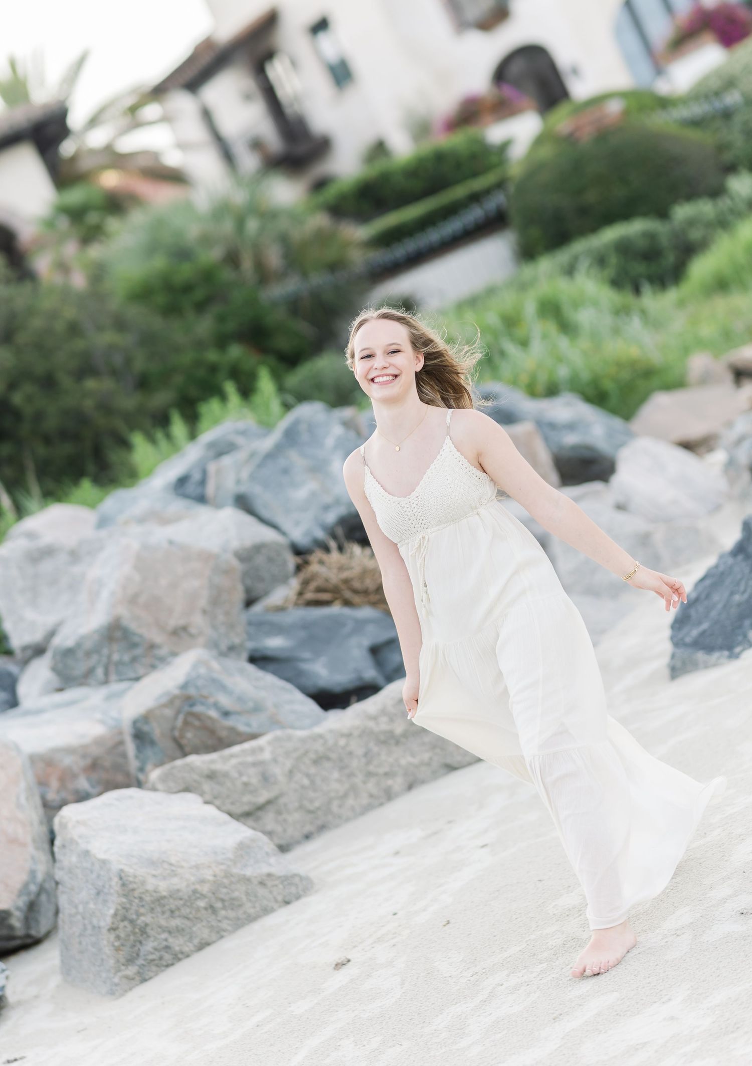 Candid seaside photo series showing movement and joy among coastal rocks in a white dress.