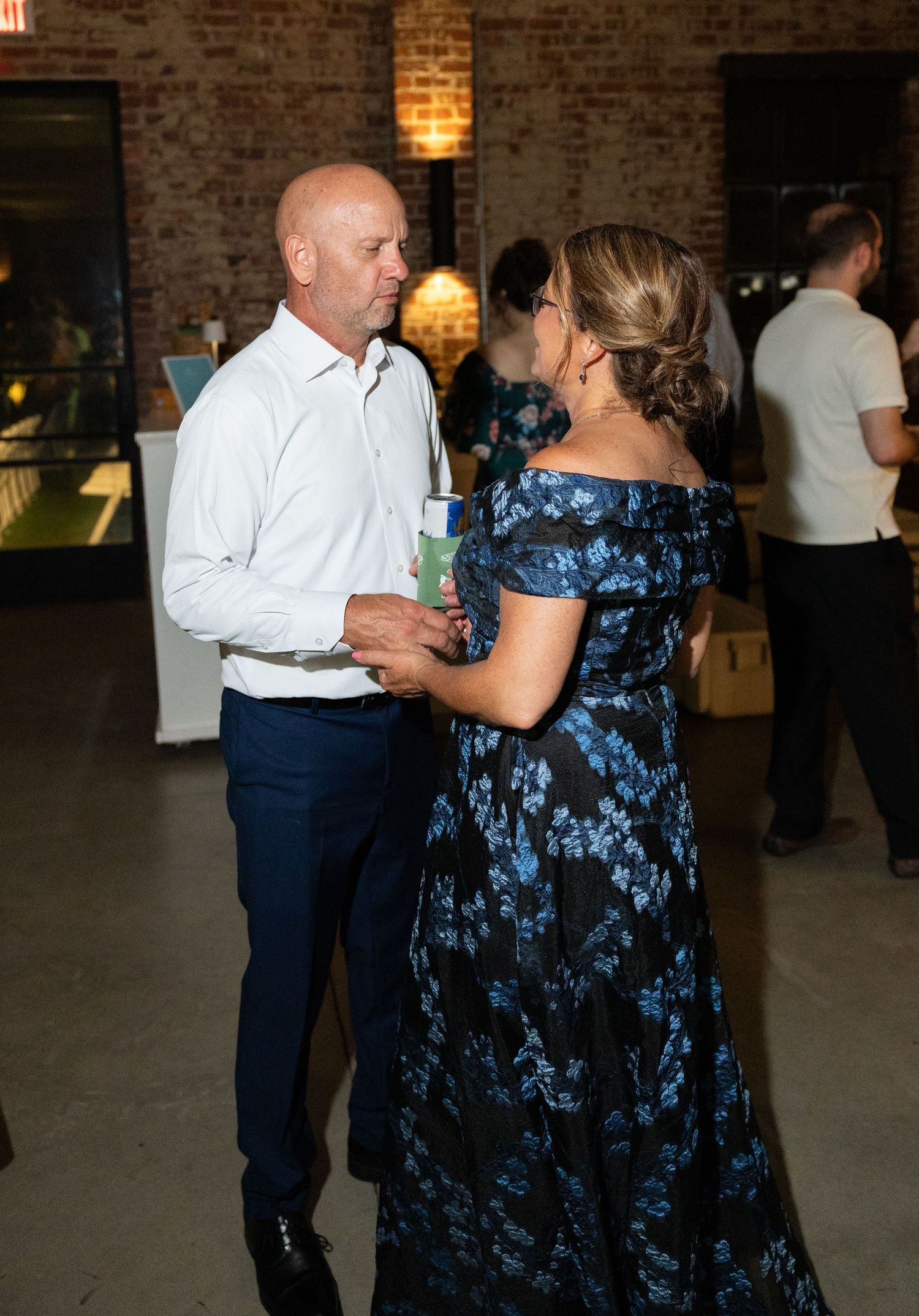 Couple dancing together at a wedding reception in a rustic brick venue.