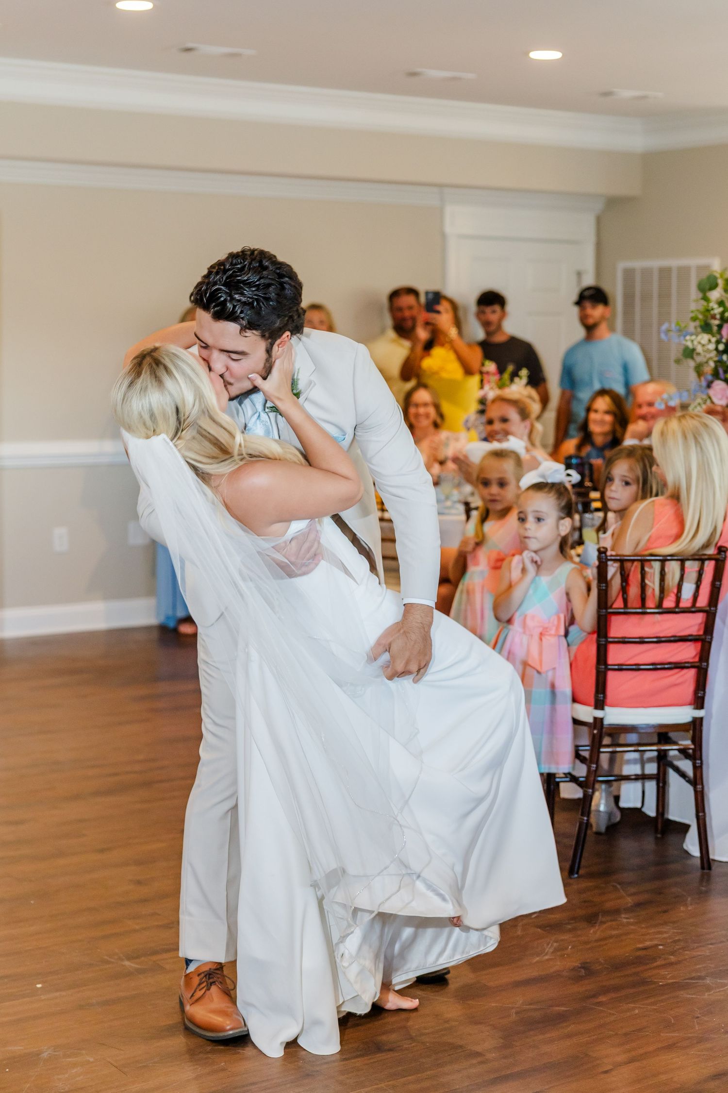 A groom dips his bride for a kiss during their first dance at a wedding reception.