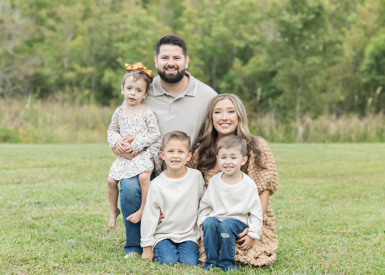 A group relaxes together on green grass during an outdoor photo session.