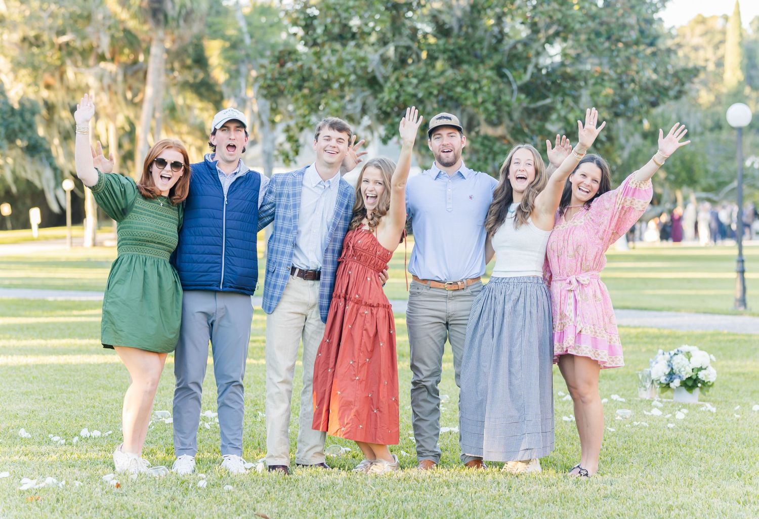 A group of friends gather in a park wearing colorful spring outfits for a celebration.