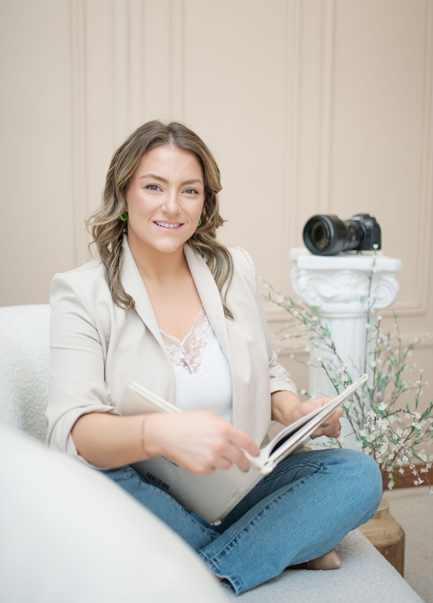 A person in casual attire relaxes on a couch while reading and taking notes in a bright, airy room with floral decor.