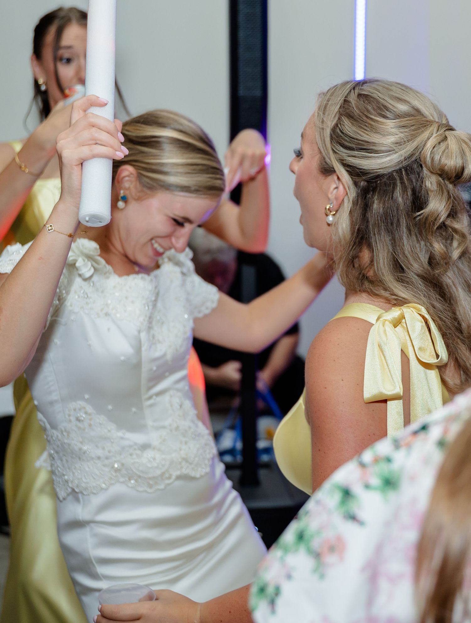 Wedding celebration features guests in white and yellow attire dancing together at an indoor venue.