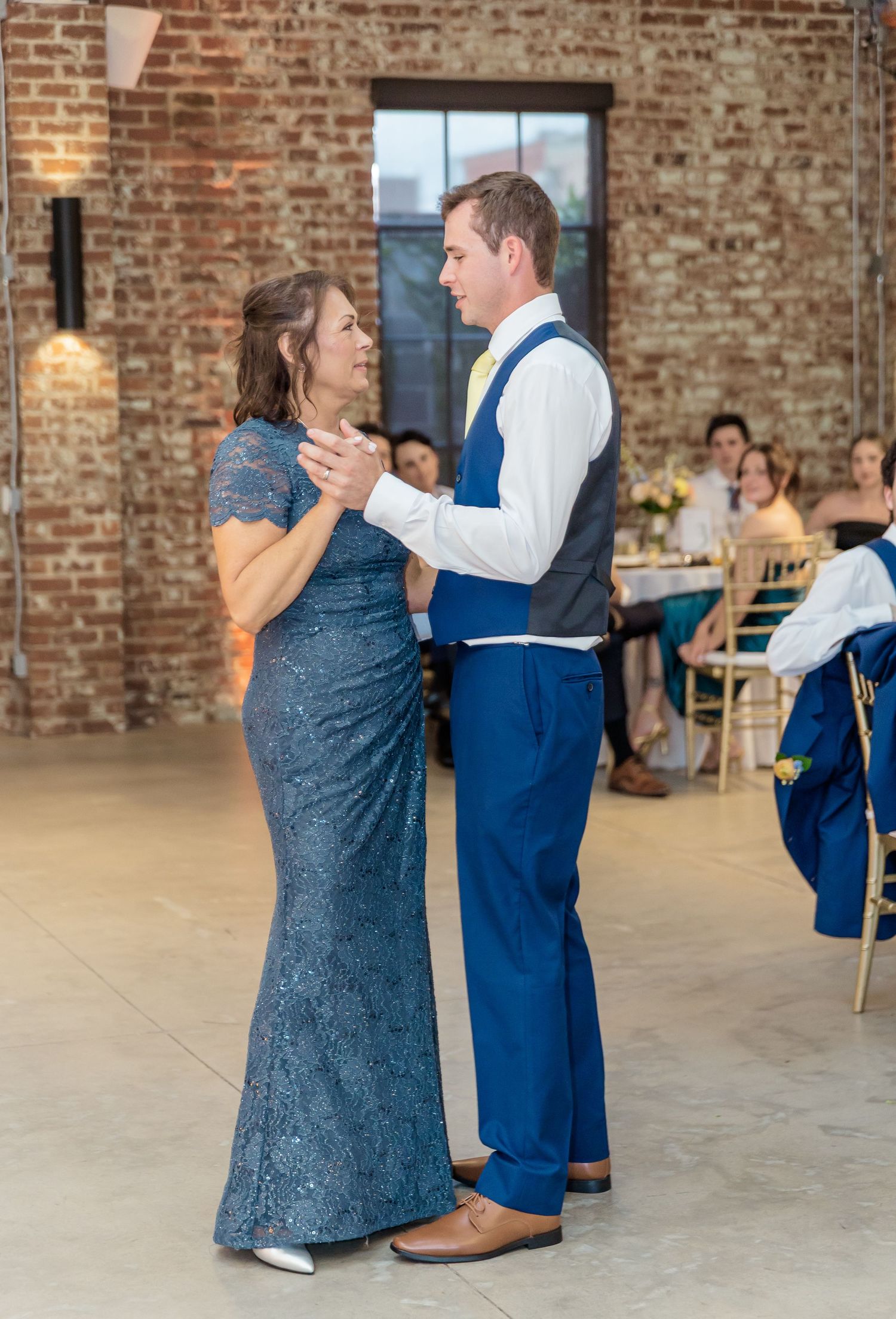 Couples dancing together in a rustic brick-walled venue with hardwood floors during a social dance event.