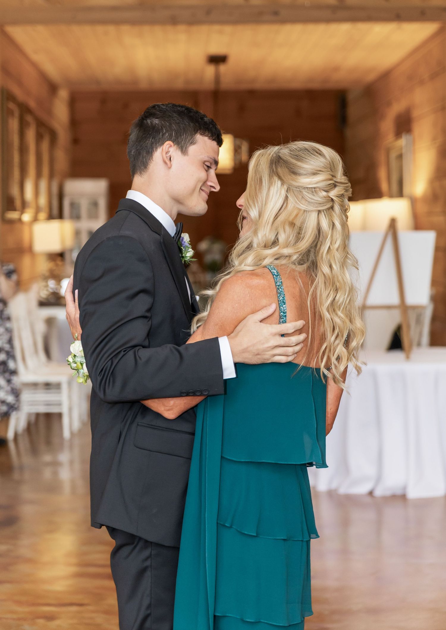 A couple embraces during their first look moment in a rustic wooden barn setting.