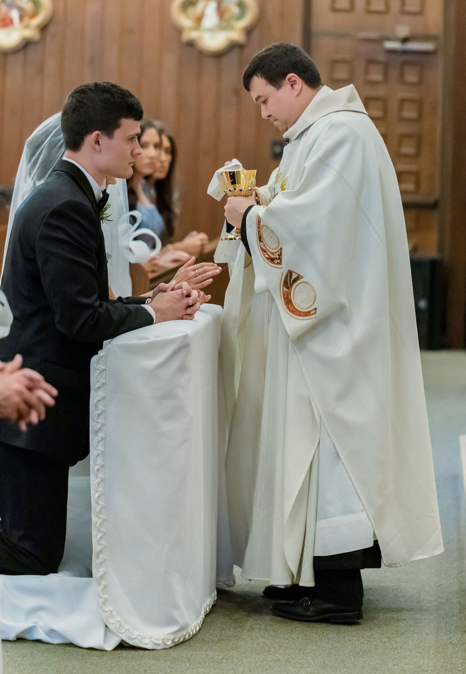 Close-up view of white-robed clergy members during a Catholic wedding ceremony.