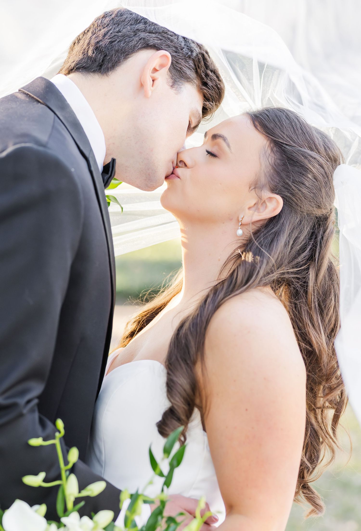 Romantic wedding couple shares intimate kiss during outdoor portrait session.