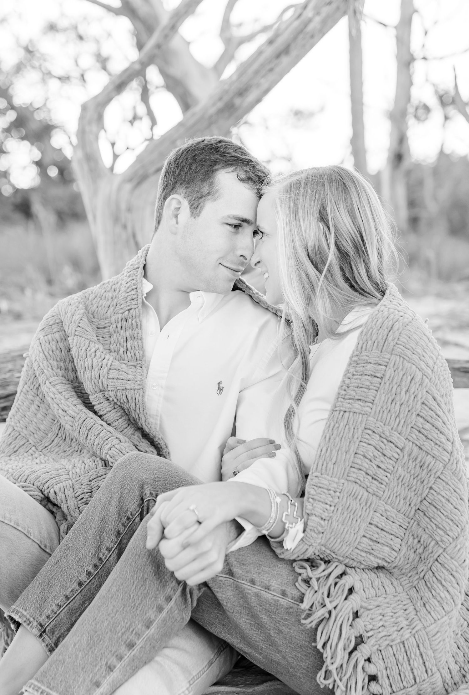Black and white photo of two people in cozy sweaters sharing a tender moment outdoors.