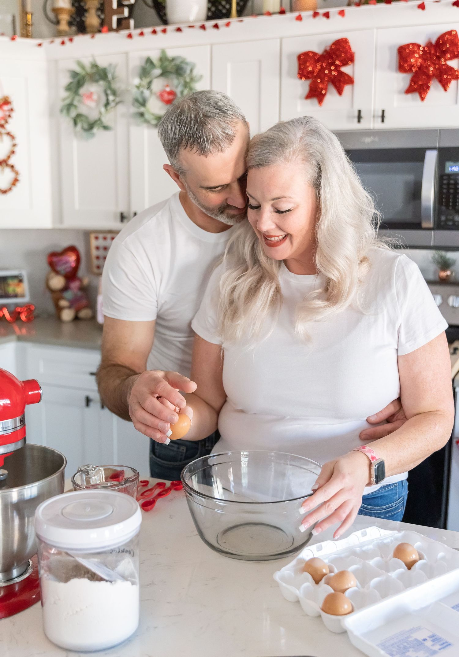 Couple baking holiday treats together in festive kitchen with Christmas decorations.