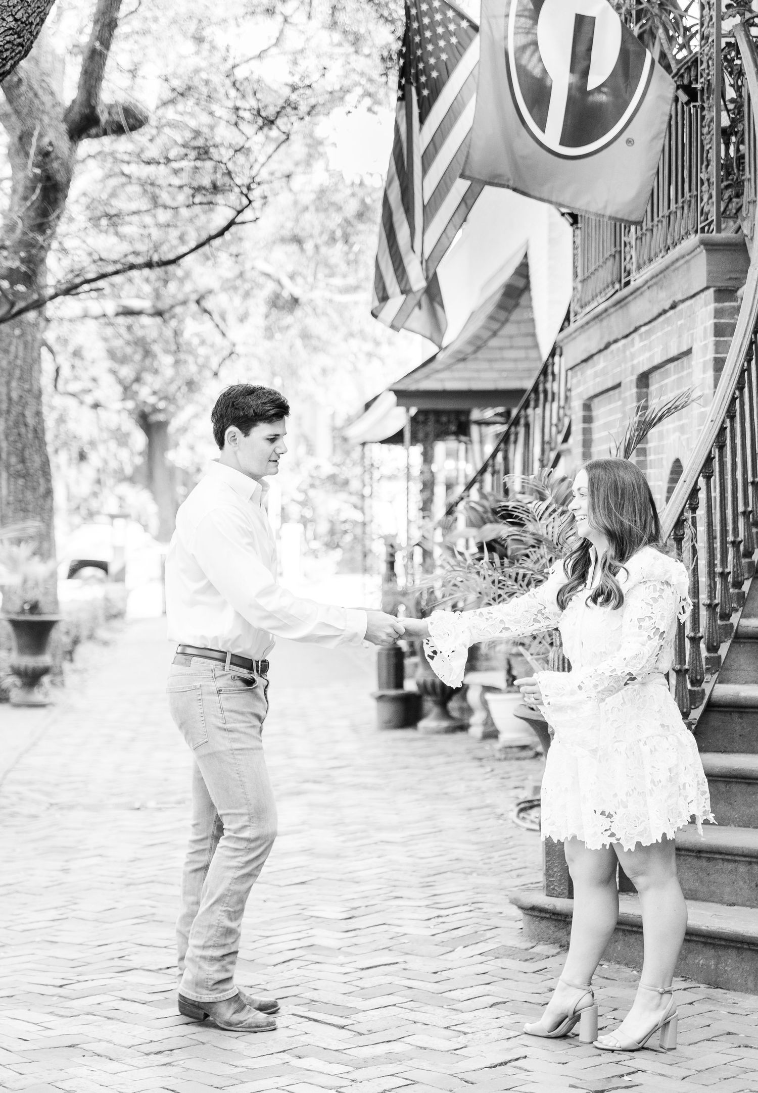 A black and white capture of a couple sharing a playful moment on brick steps.