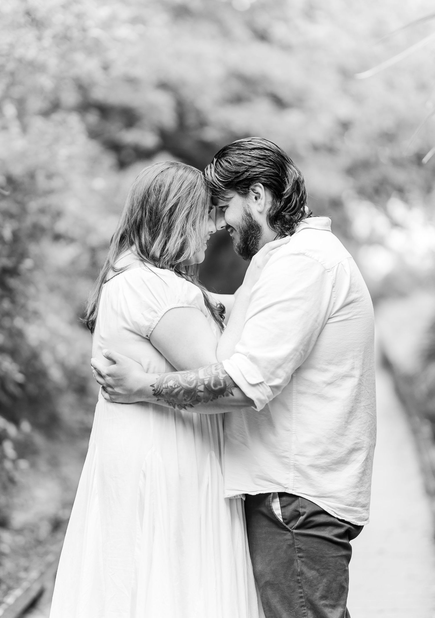 Black and white portrait of a loving couple sharing an intimate moment in a natural outdoor setting.