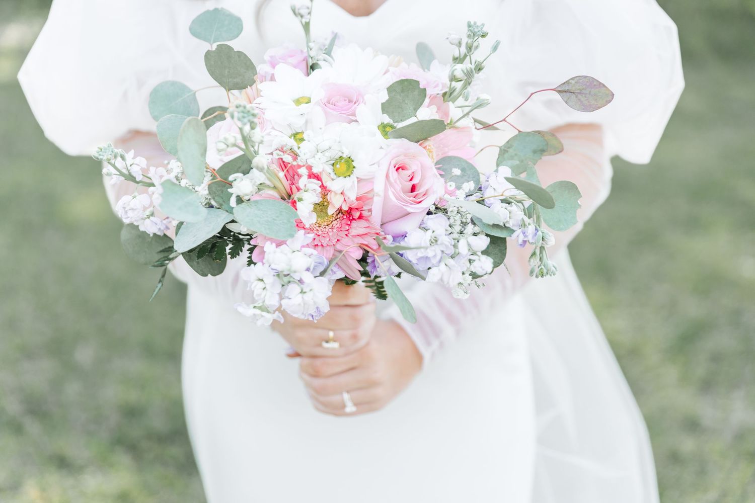 Close-up of bridal bouquet featuring pink roses, white flowers and eucalyptus leaves.
