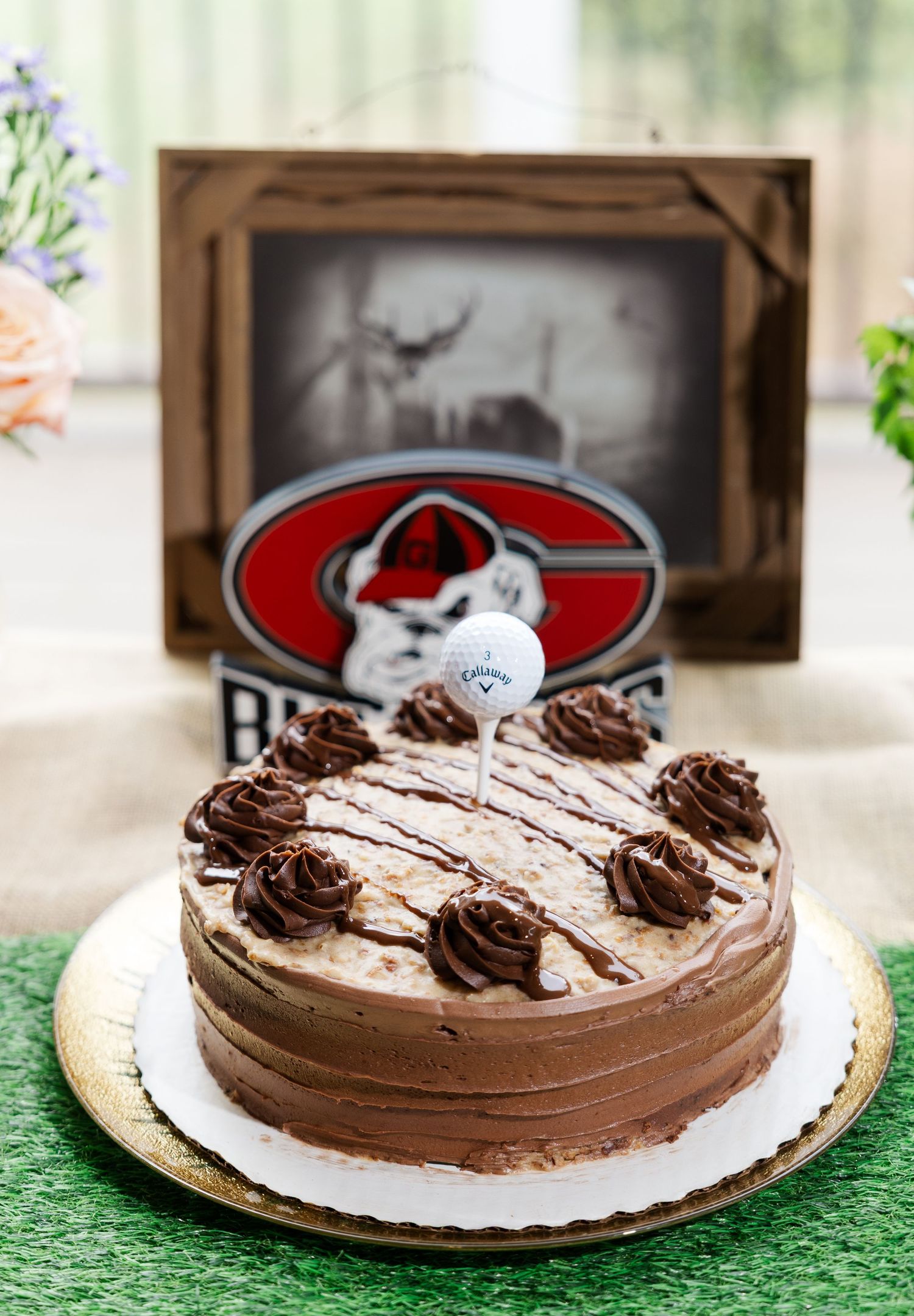 Chocolate groom's cake decorated with Georgia Bulldogs logo and Callaway golf ball topper on gold stand.