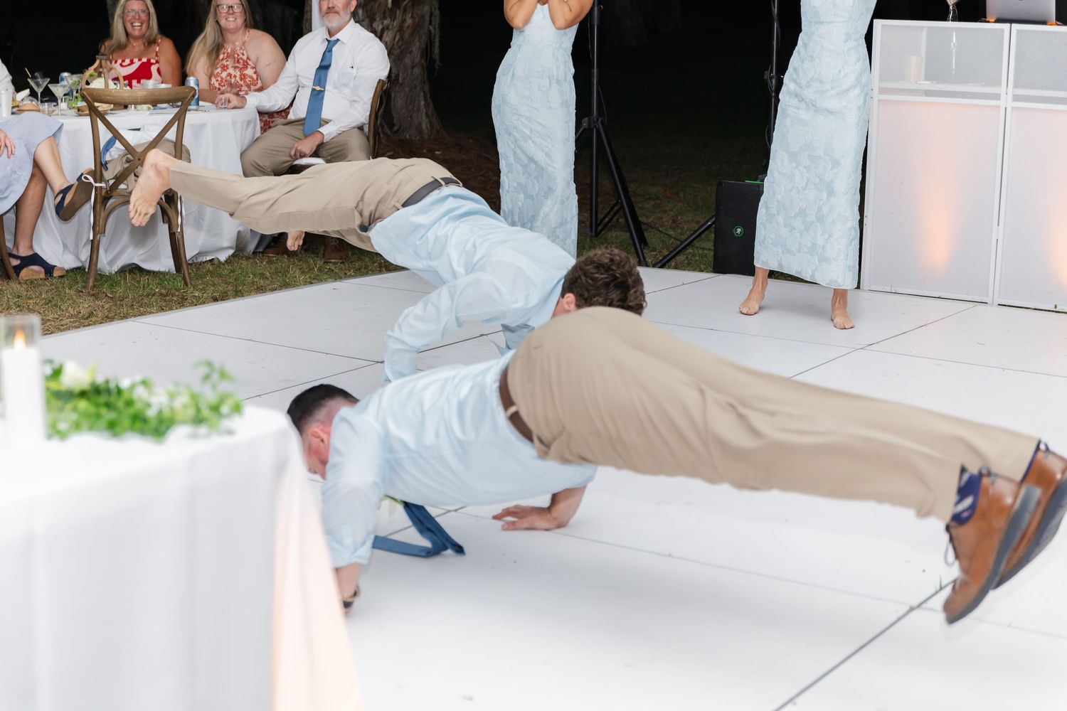 Wedding guests dancing and celebrating together on a dance floor at an outdoor reception.