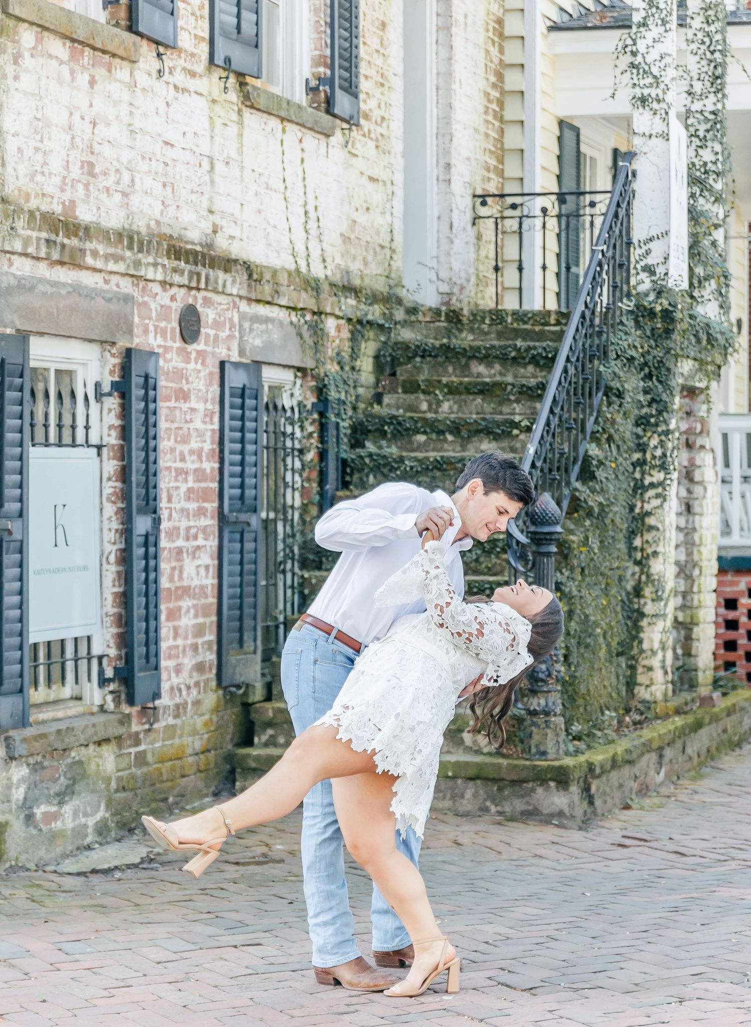 A romantic dip pose on cobblestone streets beside historic brick architecture.