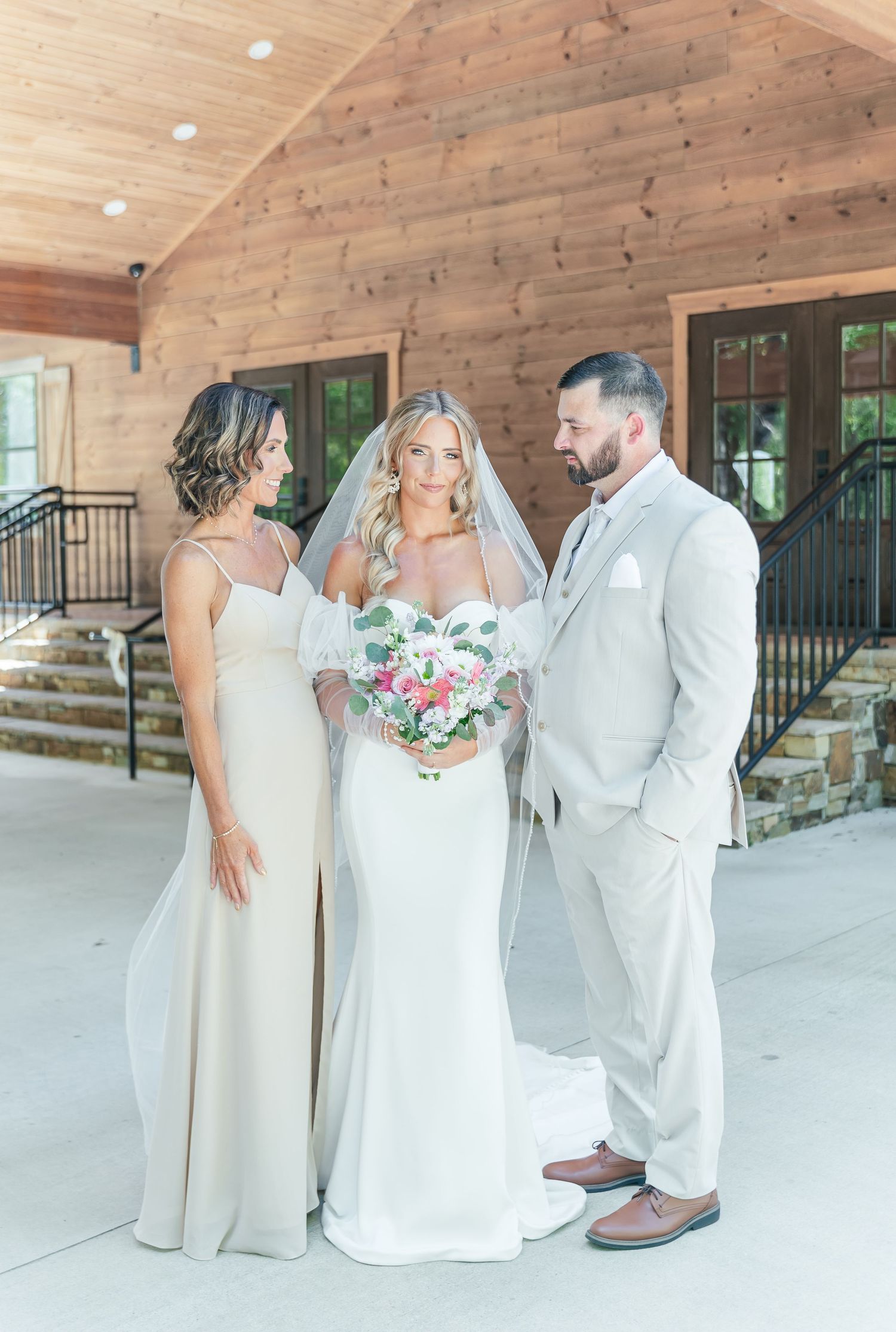Elegant bridal party poses together on porch with rustic wood paneling.