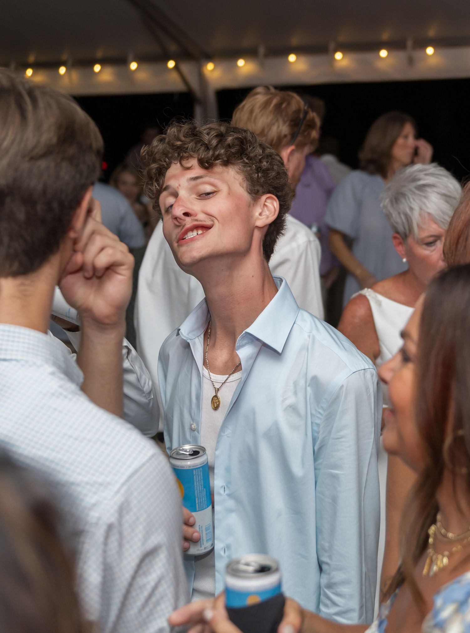 Guests enjoying a lively party atmosphere under string lights at an evening celebration.