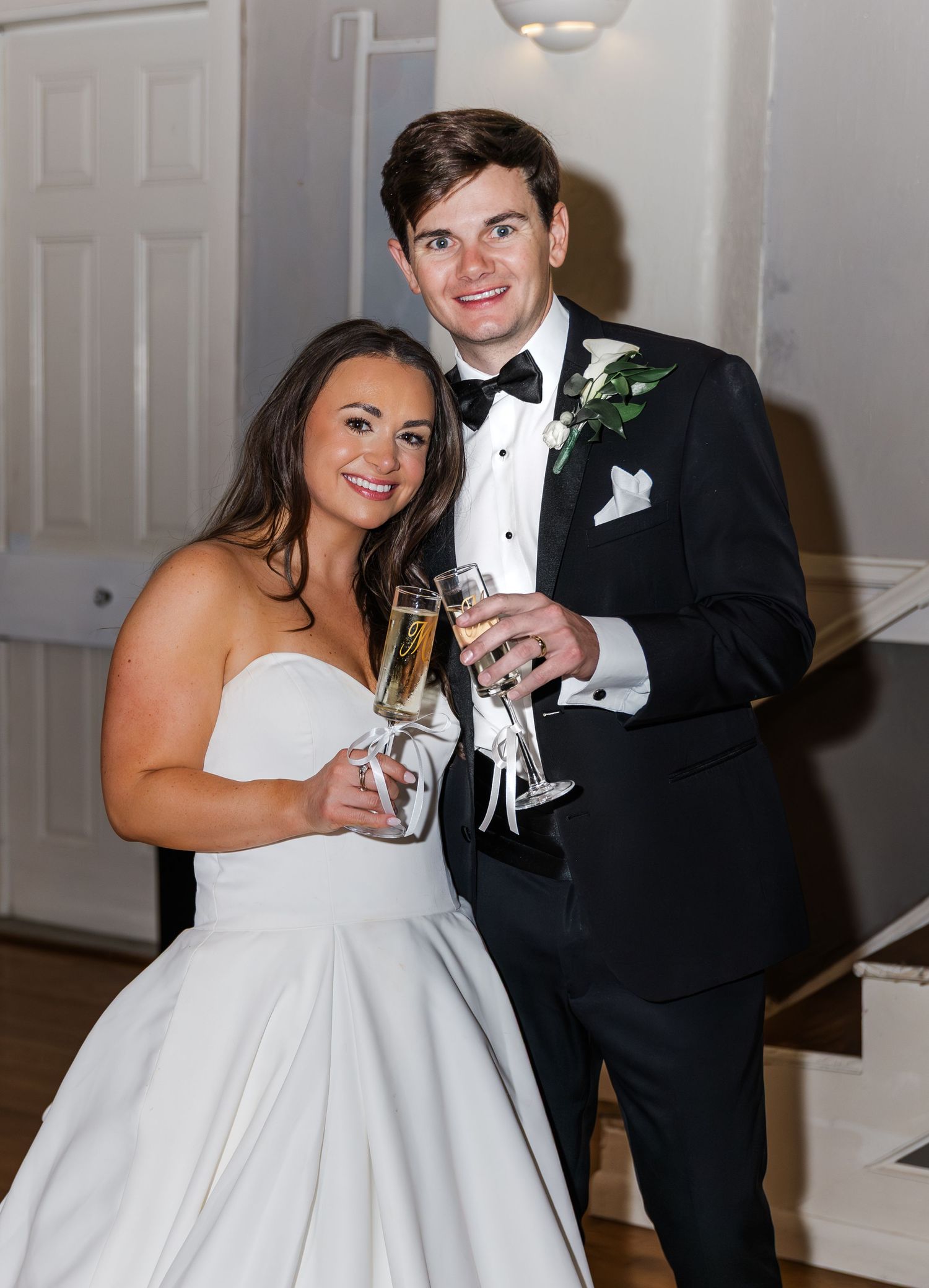 Newlyweds toasting with champagne glasses in wedding attire at their reception.