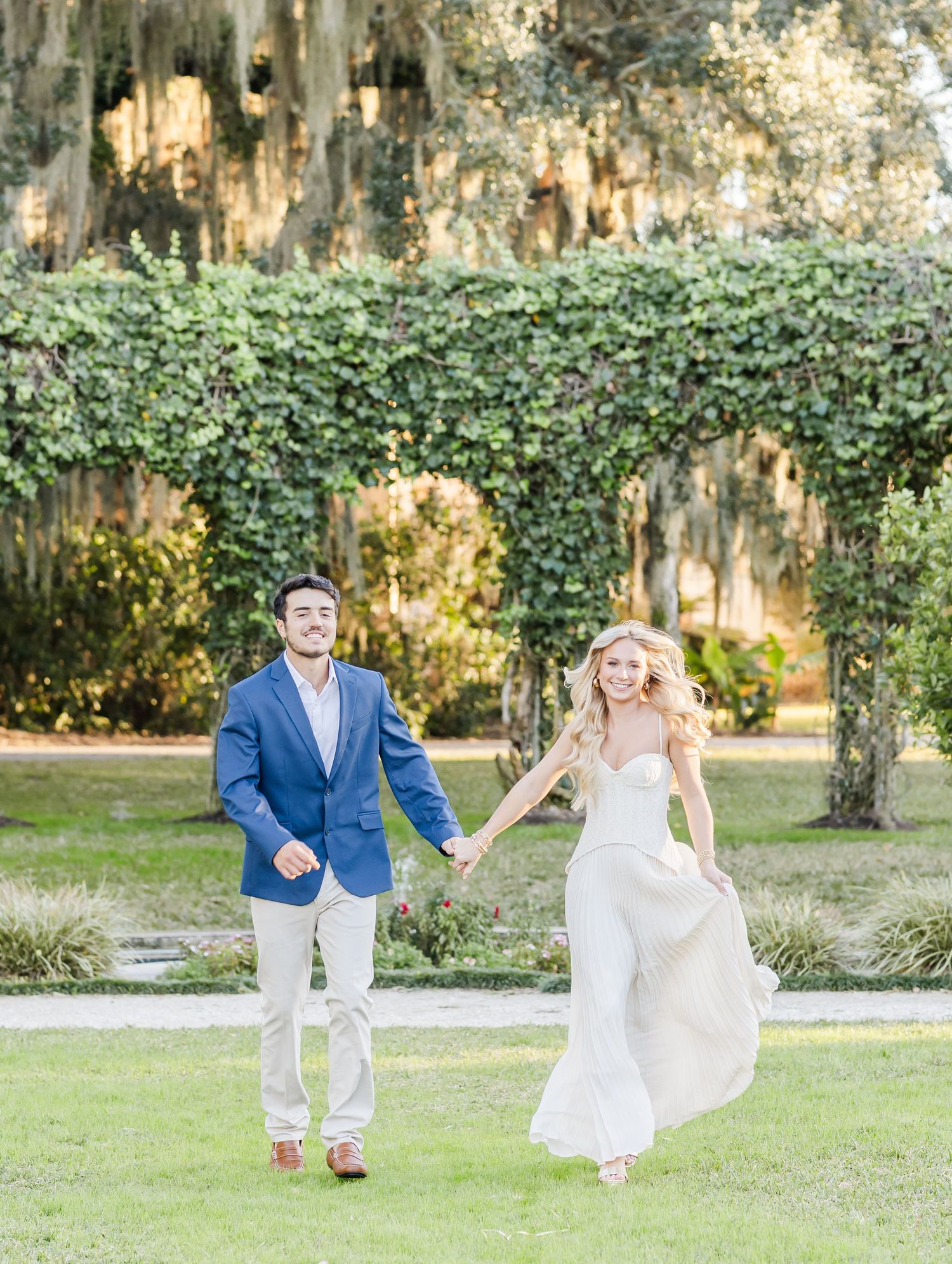 A playful engagement session with a couple dancing and twirling in a garden setting.