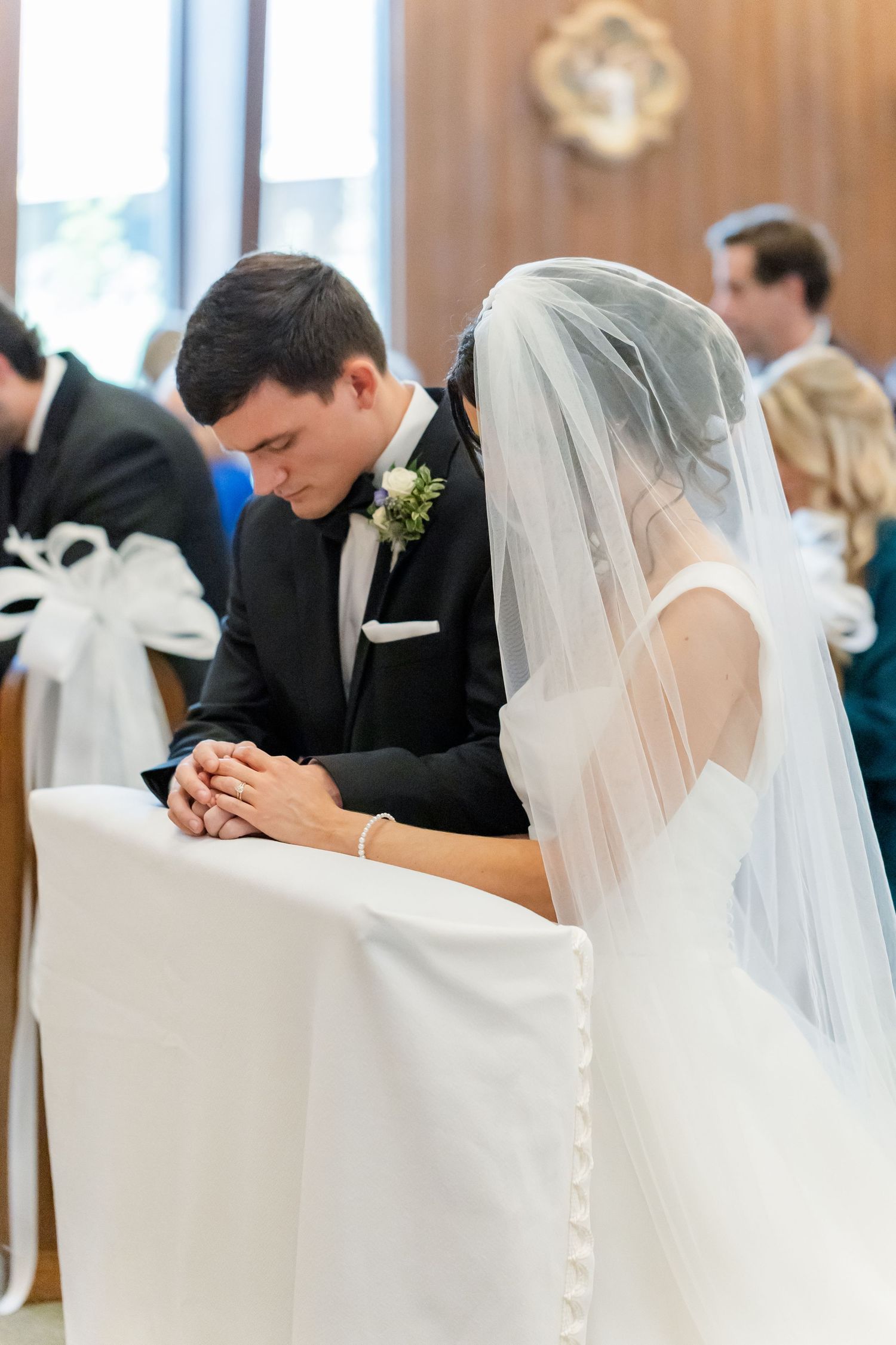 Wedding couple and guests seated in church pews during a solemn ceremony moment.