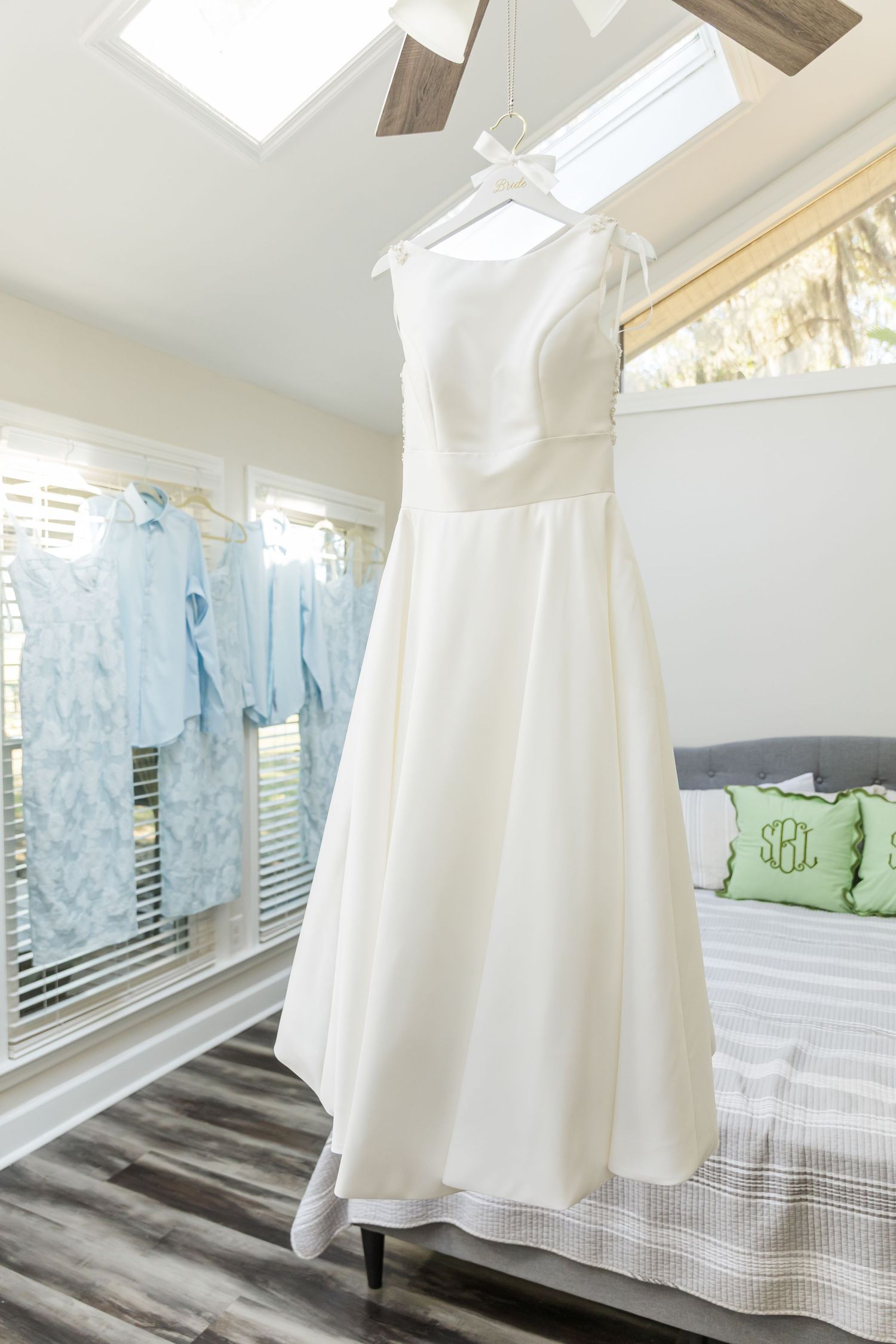 White sheets and clothing hanging to dry on a clothesline indoors with natural light streaming through windows.