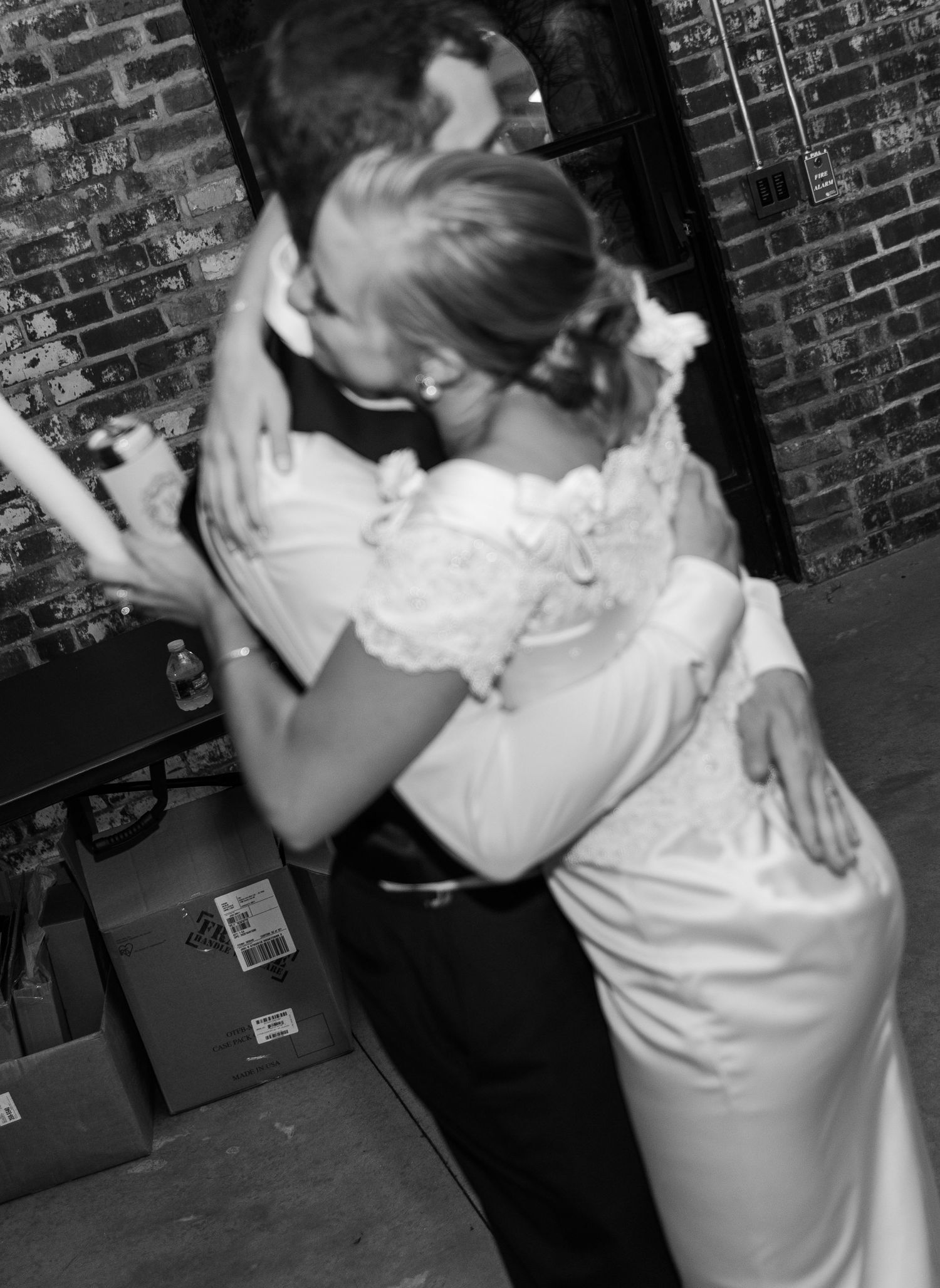 Black and white photo of couples dancing at a formal event near brick walls.