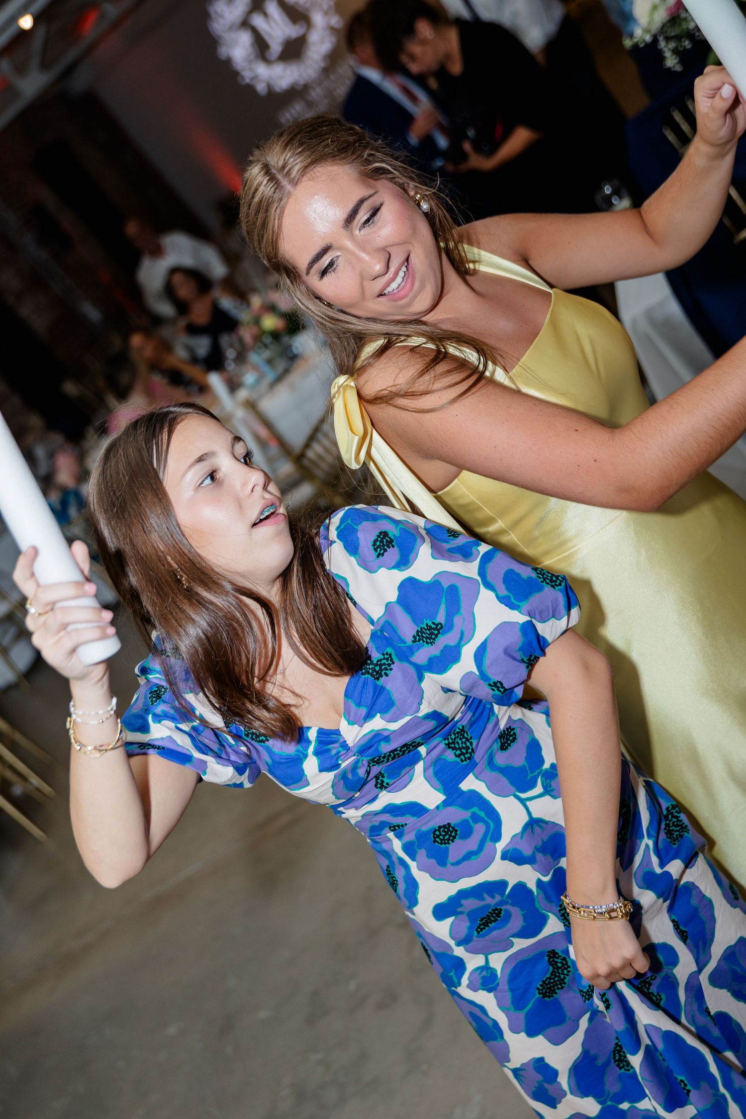 Guests dance energetically while holding glowing foam sticks at a celebration.