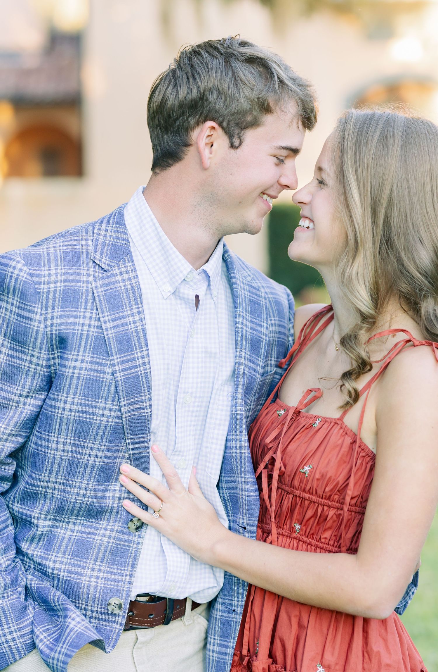 A tender moment shared between a couple in formal wear against an architectural backdrop.