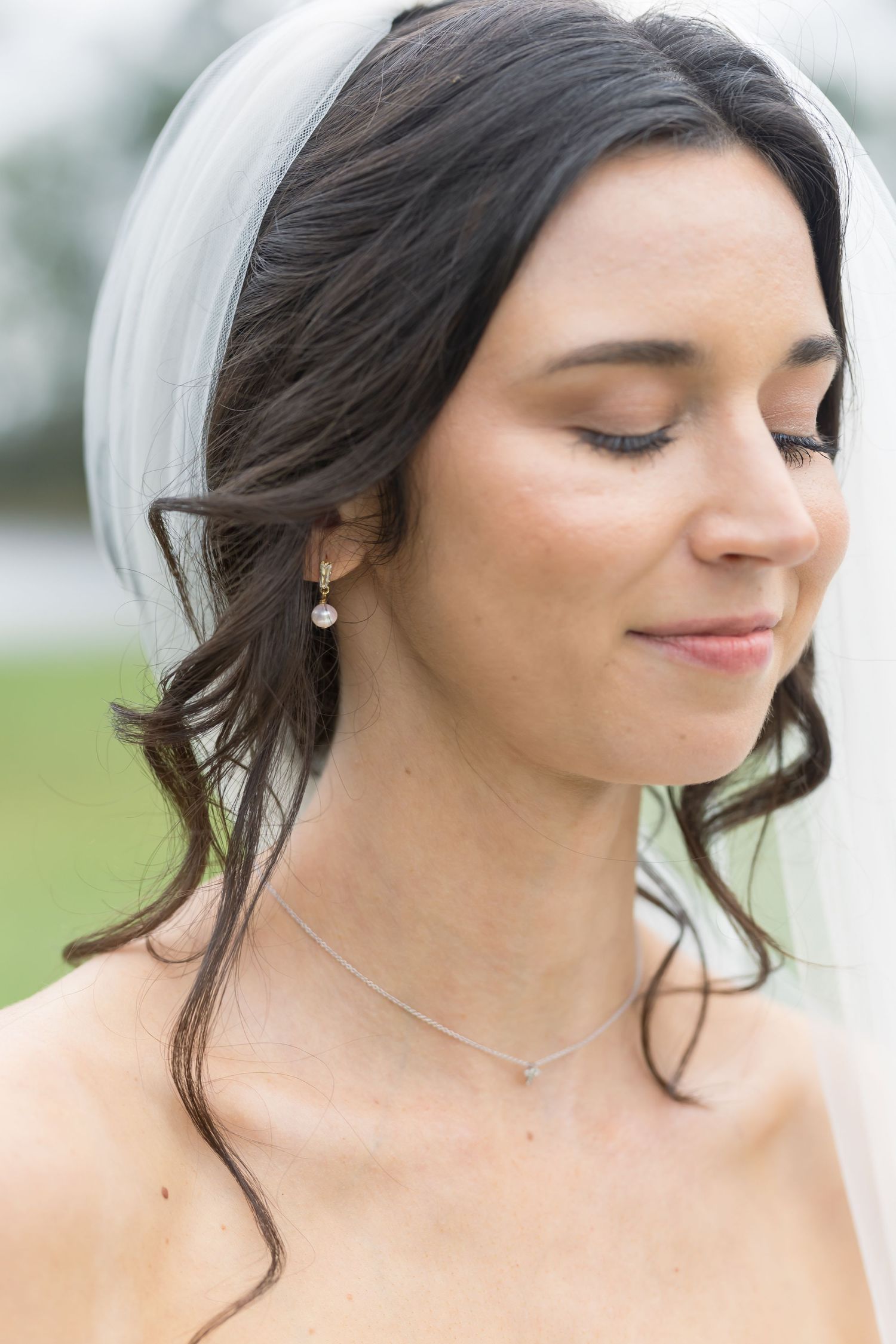 Close-up portrait showing delicate bridal makeup and jewelry details.