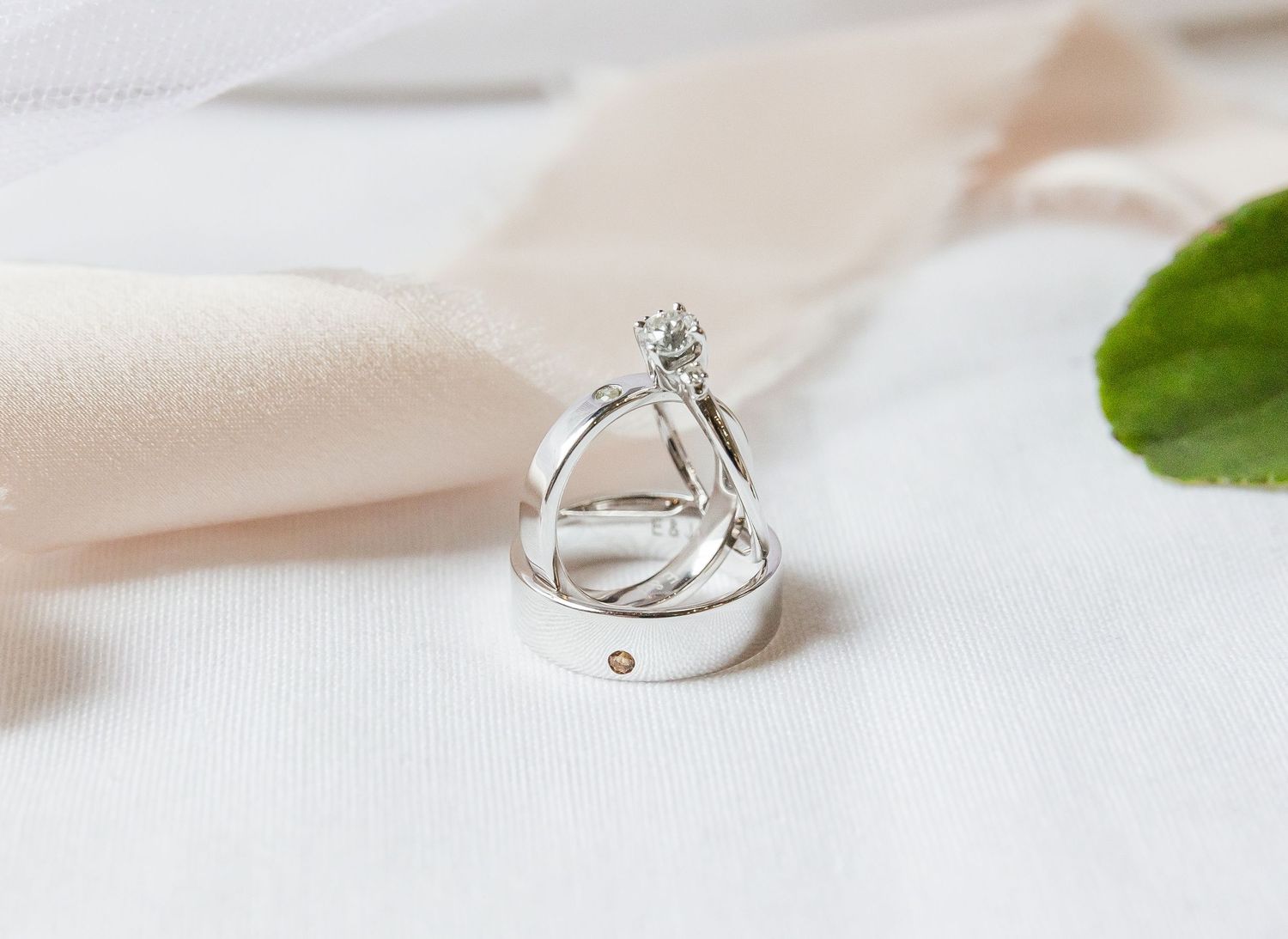 Delicate silver and diamond engagement rings displayed in a minimalist row with soft white fabric backdrop.