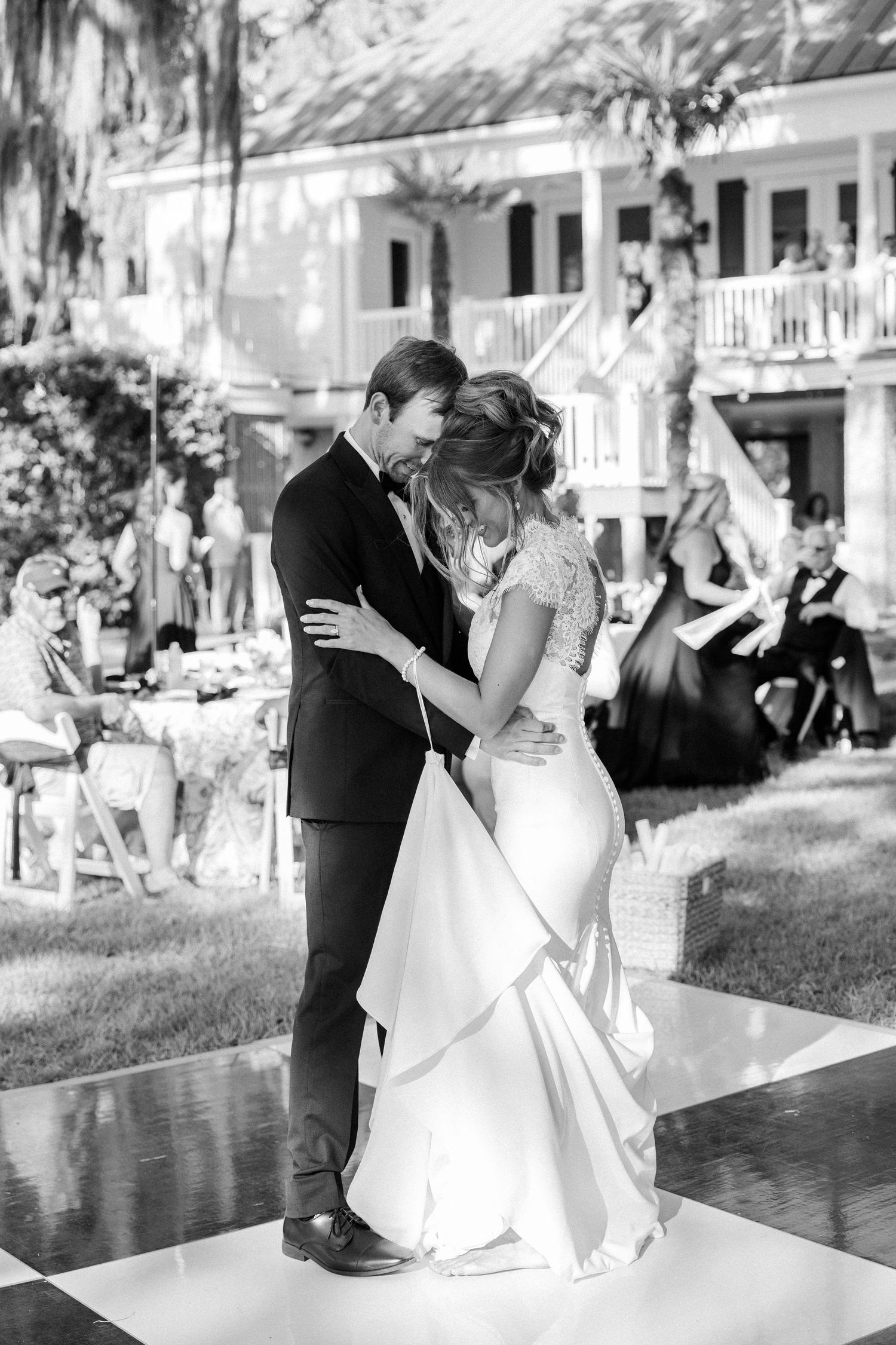 Bride and groom share their first dance on a checkered floor at an outdoor wedding reception.