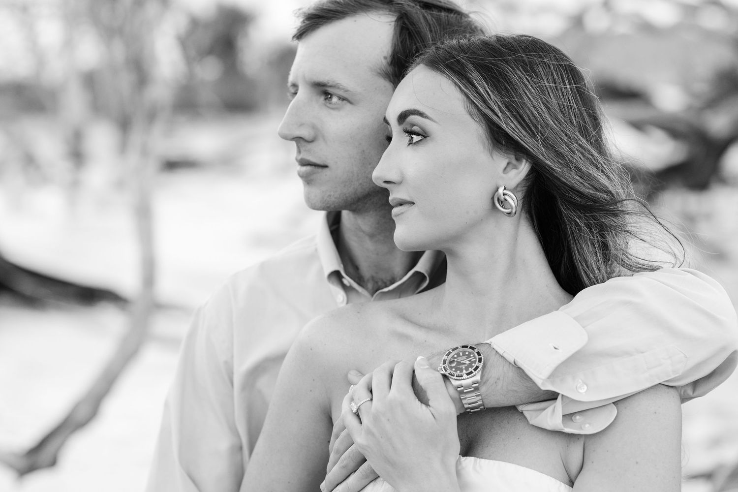 Black and white close-up of couple gazing into the distance together on a sunny beach.