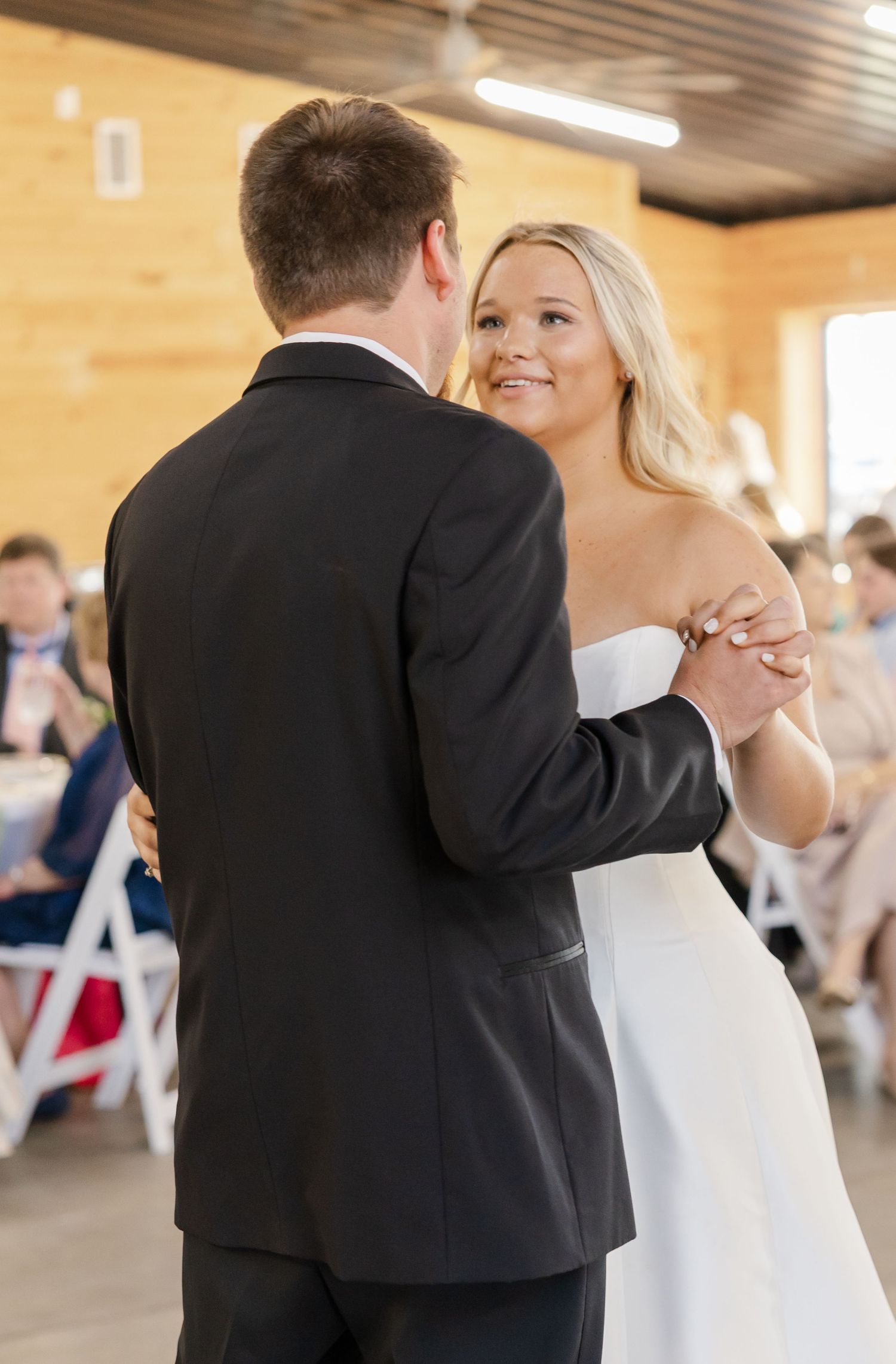 Bride and groom sharing first dance at rustic barn wedding reception.