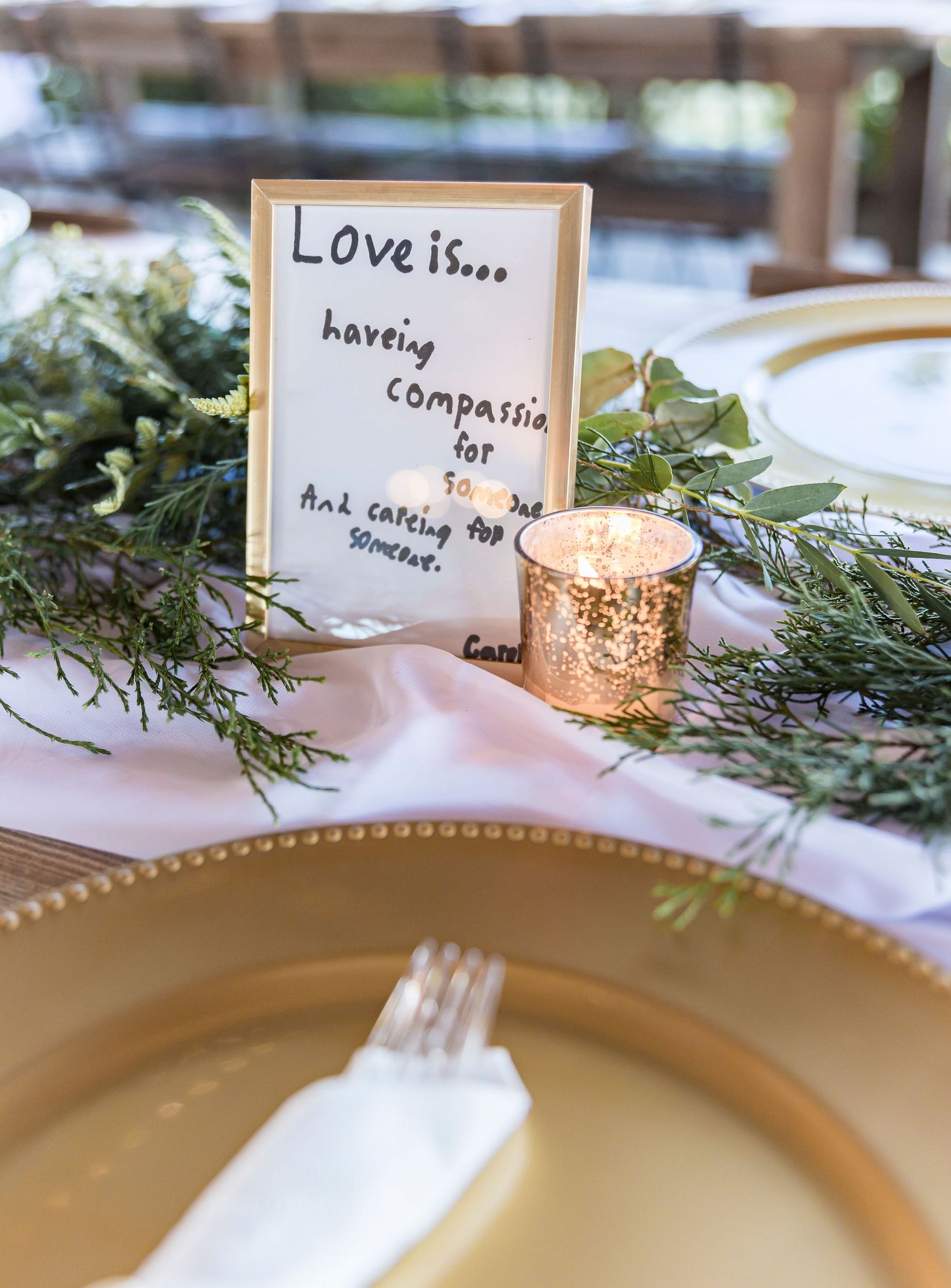 Wedding reception table setting with handwritten love quote and gold votives.