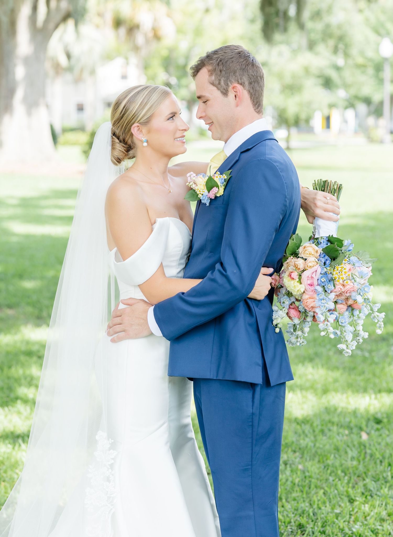 A romantic wedding portrait with the couple embracing in a sunlit garden setting.