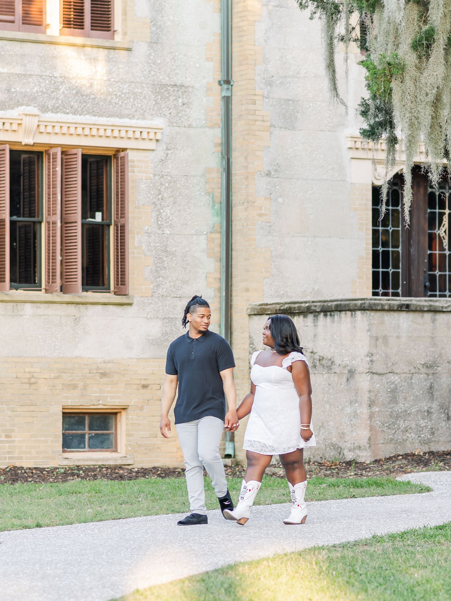 Couple walking along a stone path outside a grand historic building.