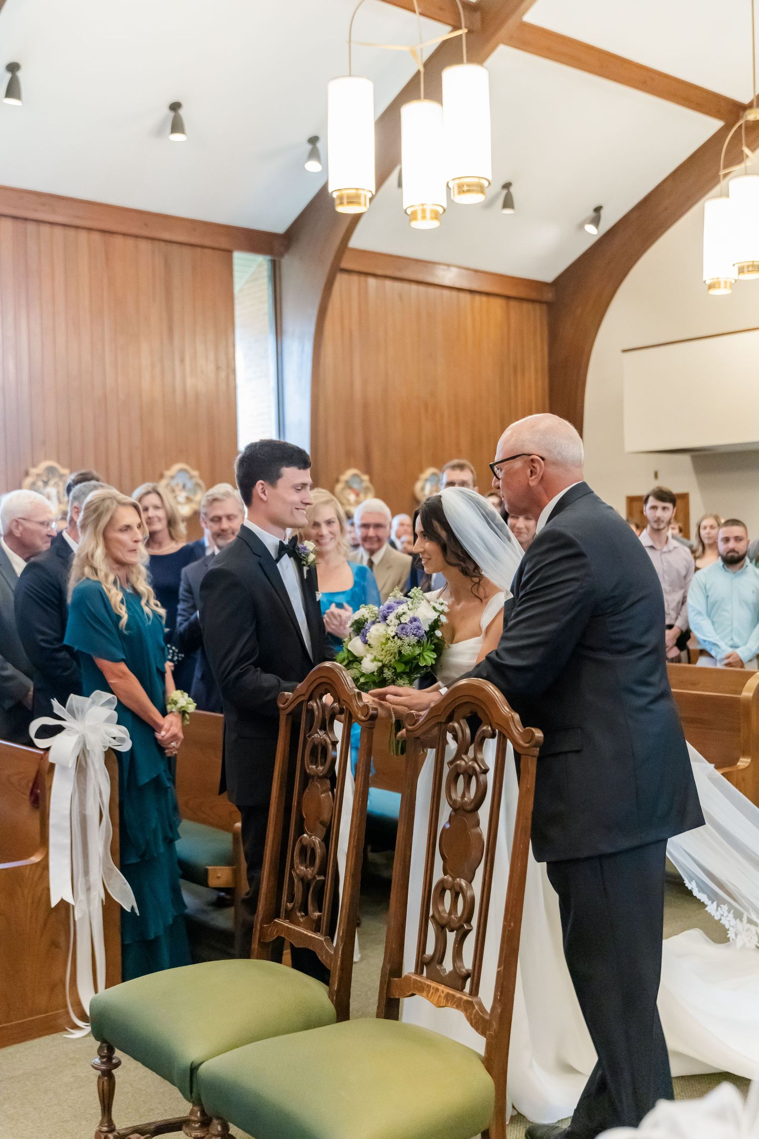 Wedding guests and family members gathering in church aisle after ceremony.