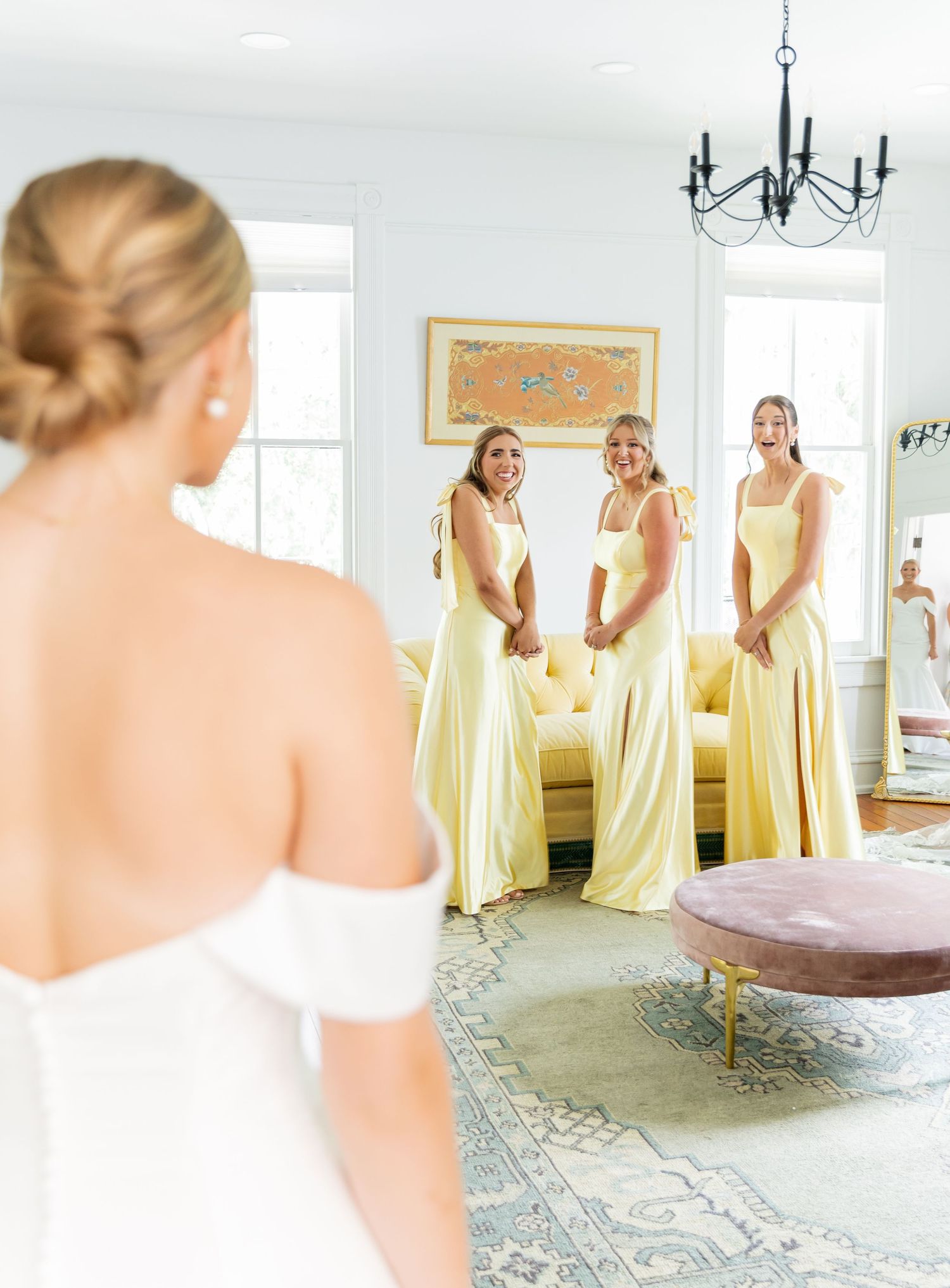 Bridesmaids in pale yellow dresses gather around a bride in a white gown during pre-wedding preparations.