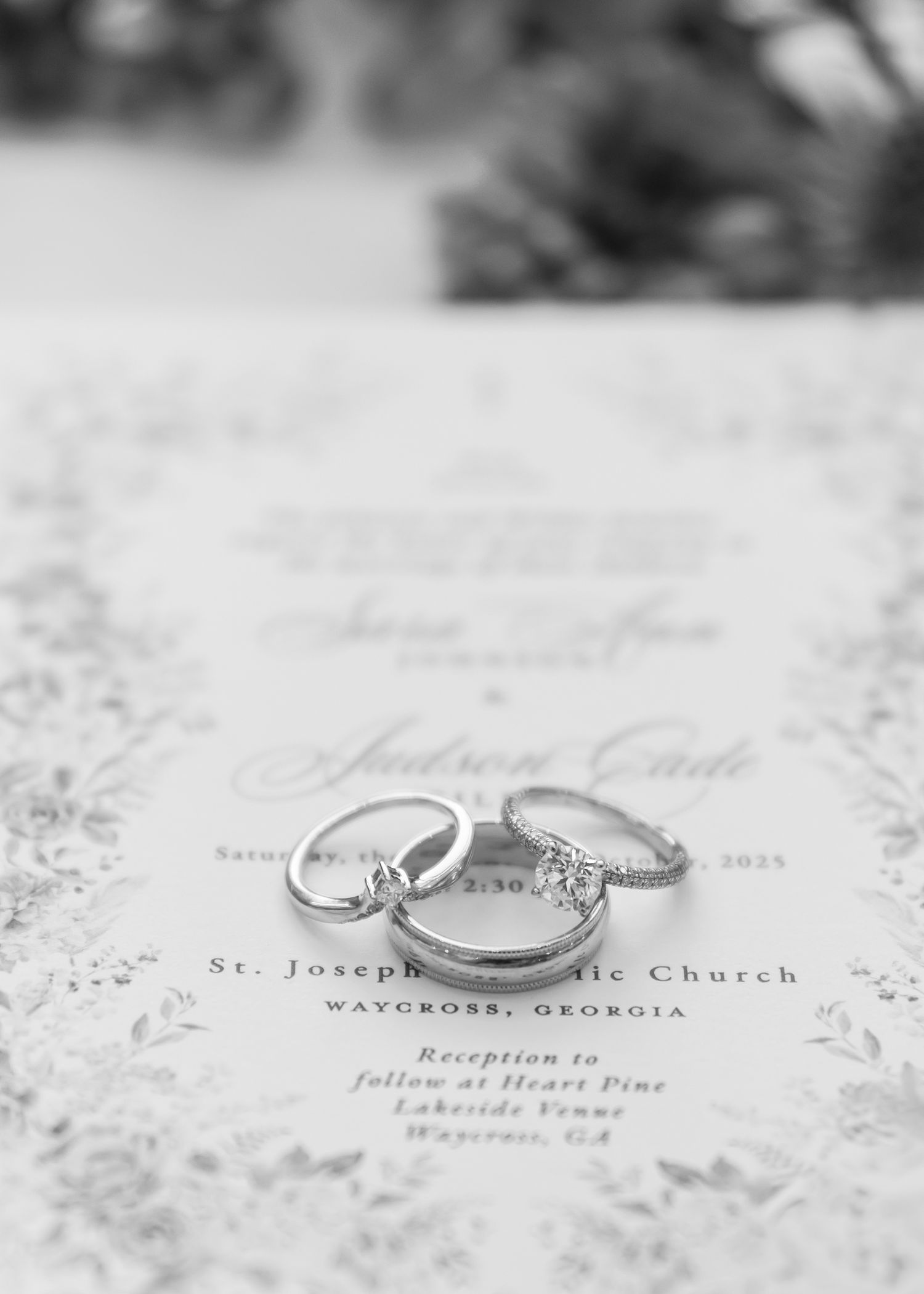 Wedding rings photographed in black and white on a printed invitation with elegant text details.