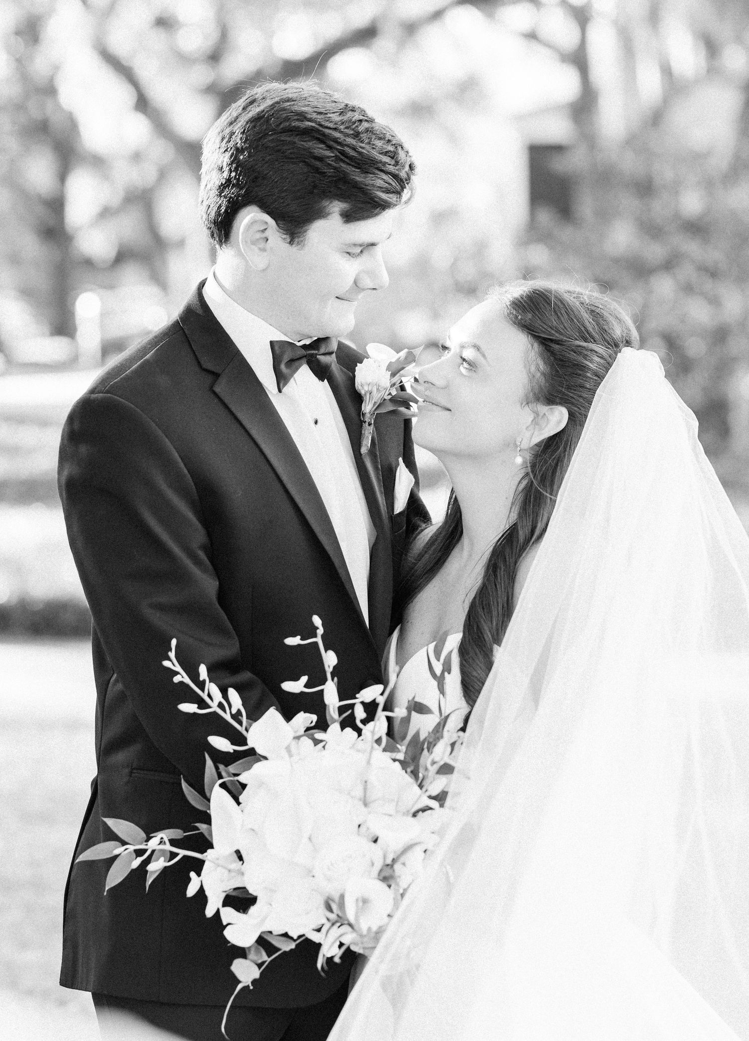 Black and white portrait of bride and groom gazing at each other outdoors at wedding.