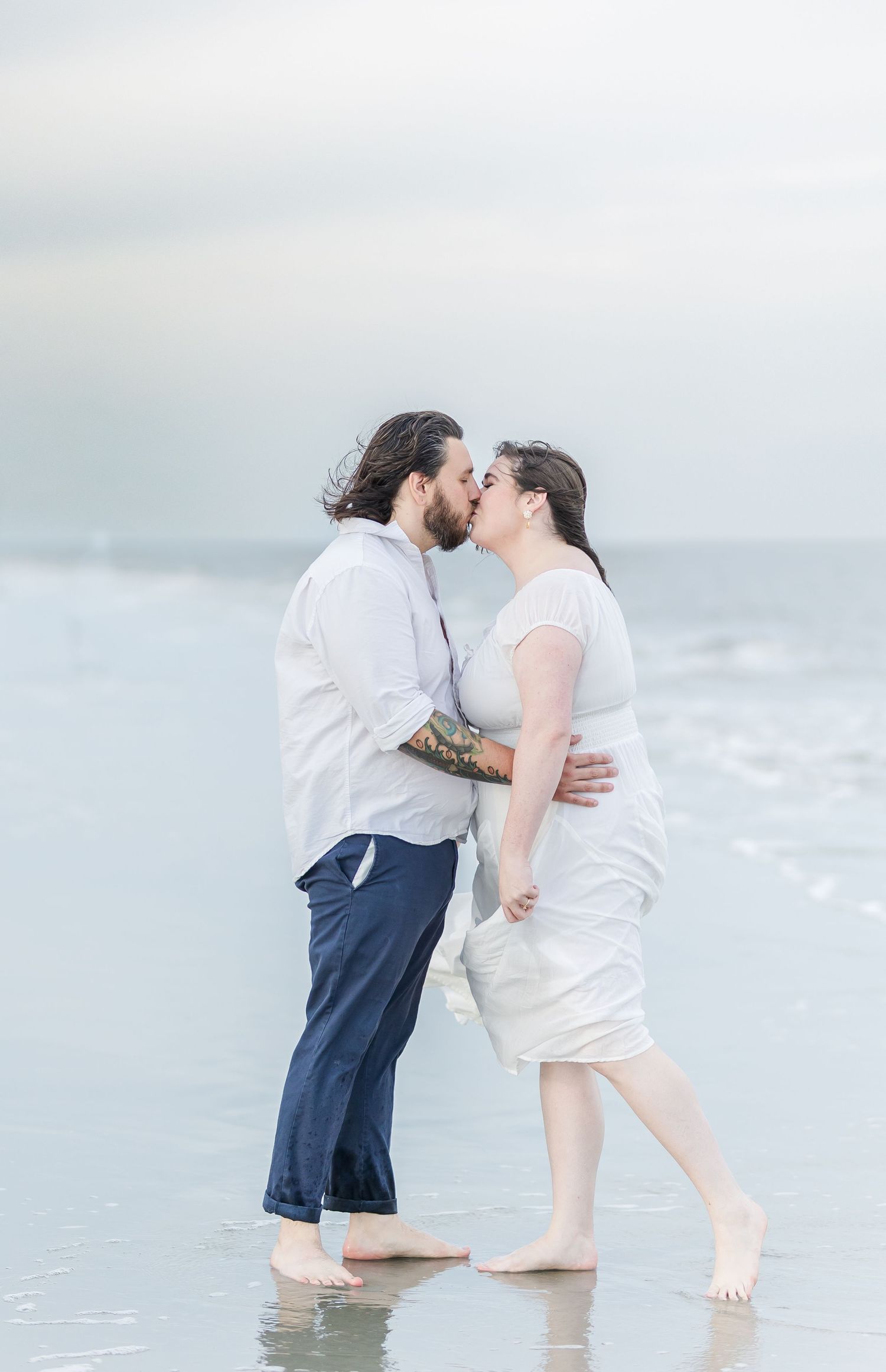 A romantic couple shares an intimate moment while standing in shallow ocean waters.