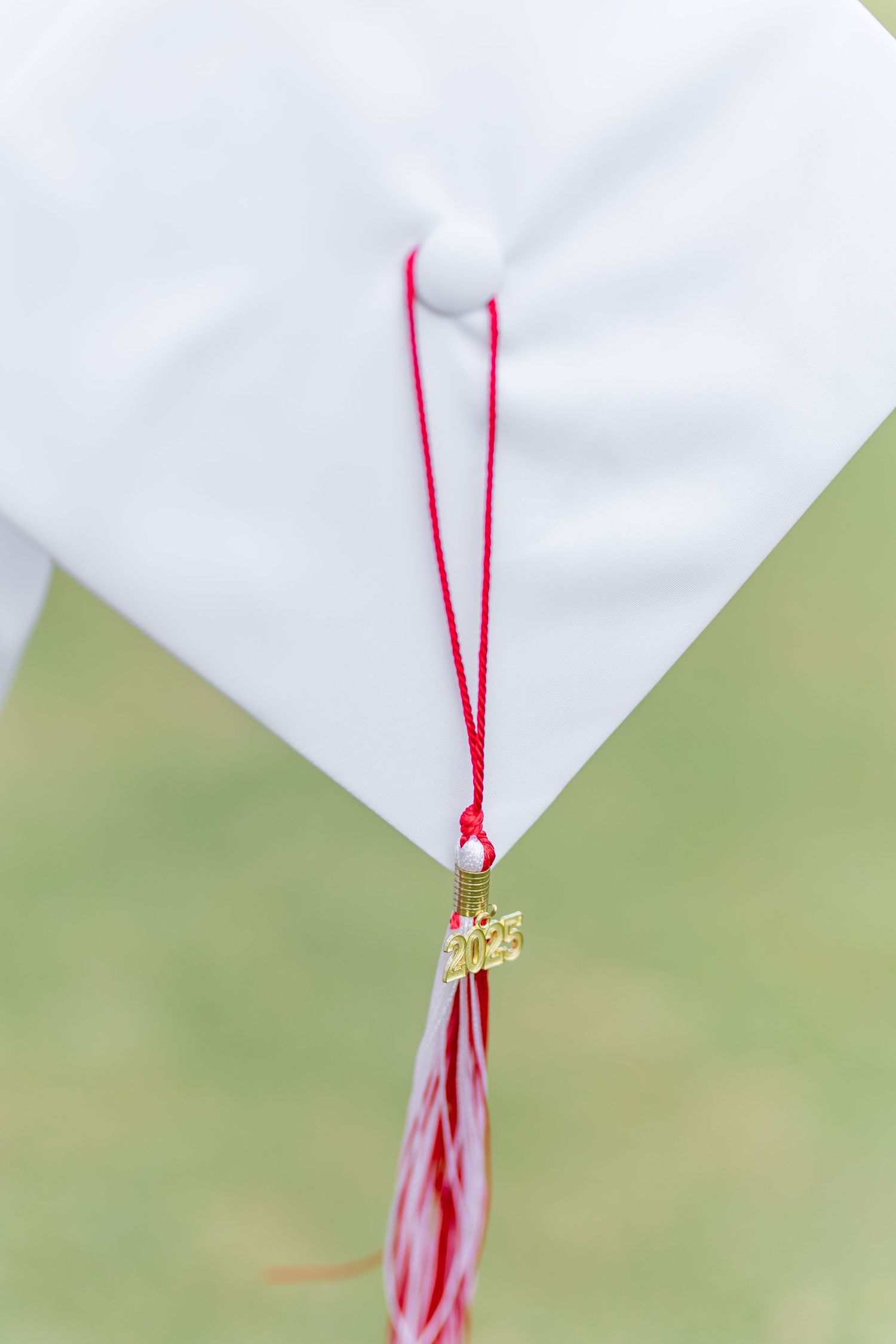 A close-up of a red and white graduation tassel hanging from a corner.