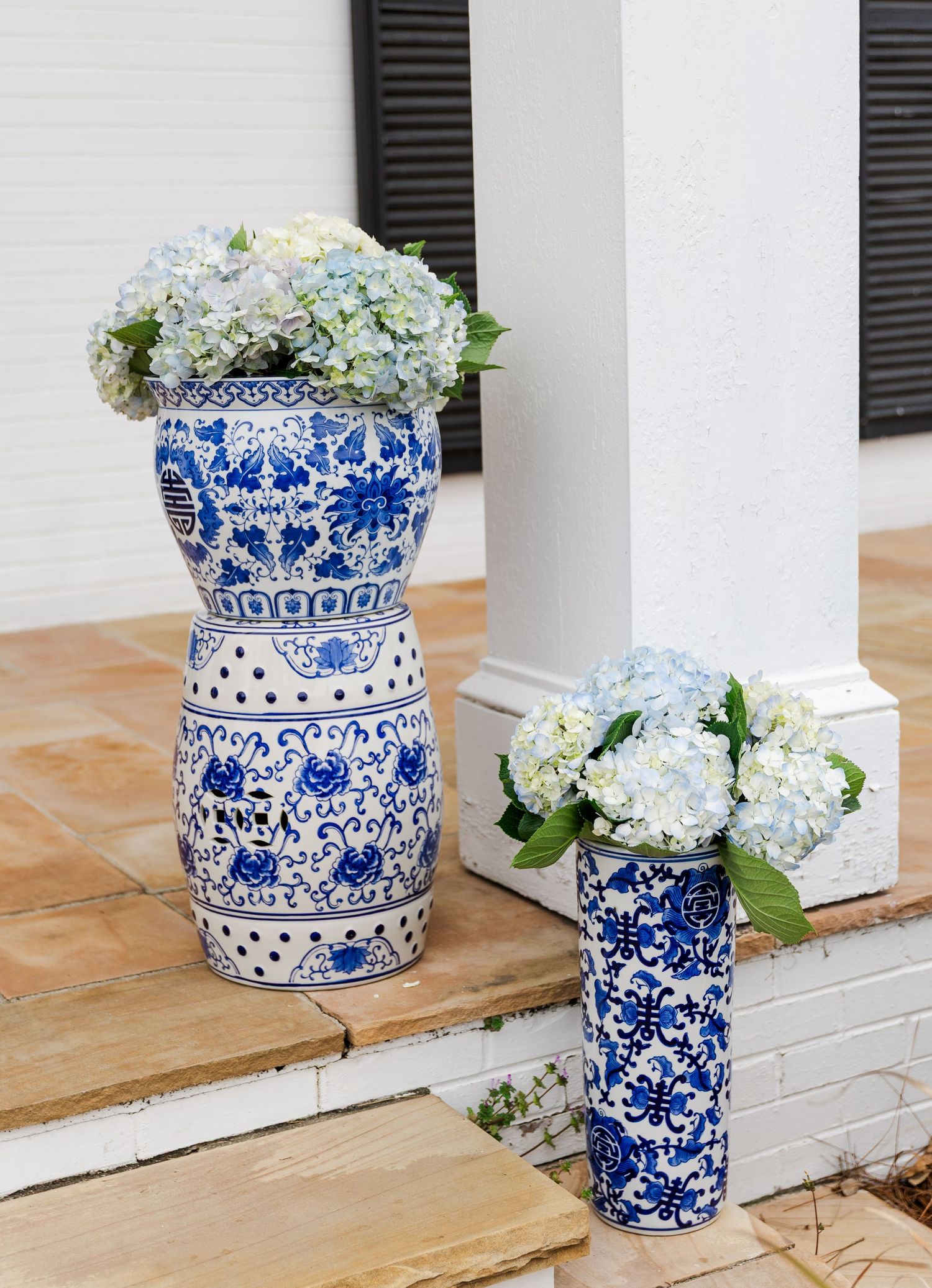 Blue and white chinoiserie ceramic vases filled with hydrangeas decorating a classic Southern home's front steps.