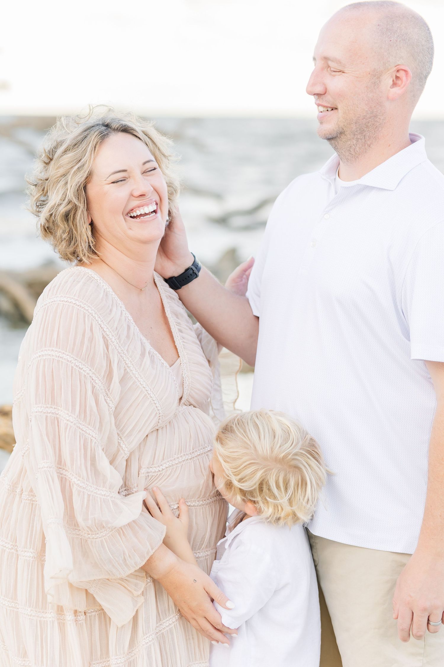 A family shares a joyful moment together on the beach in soft neutral colors.