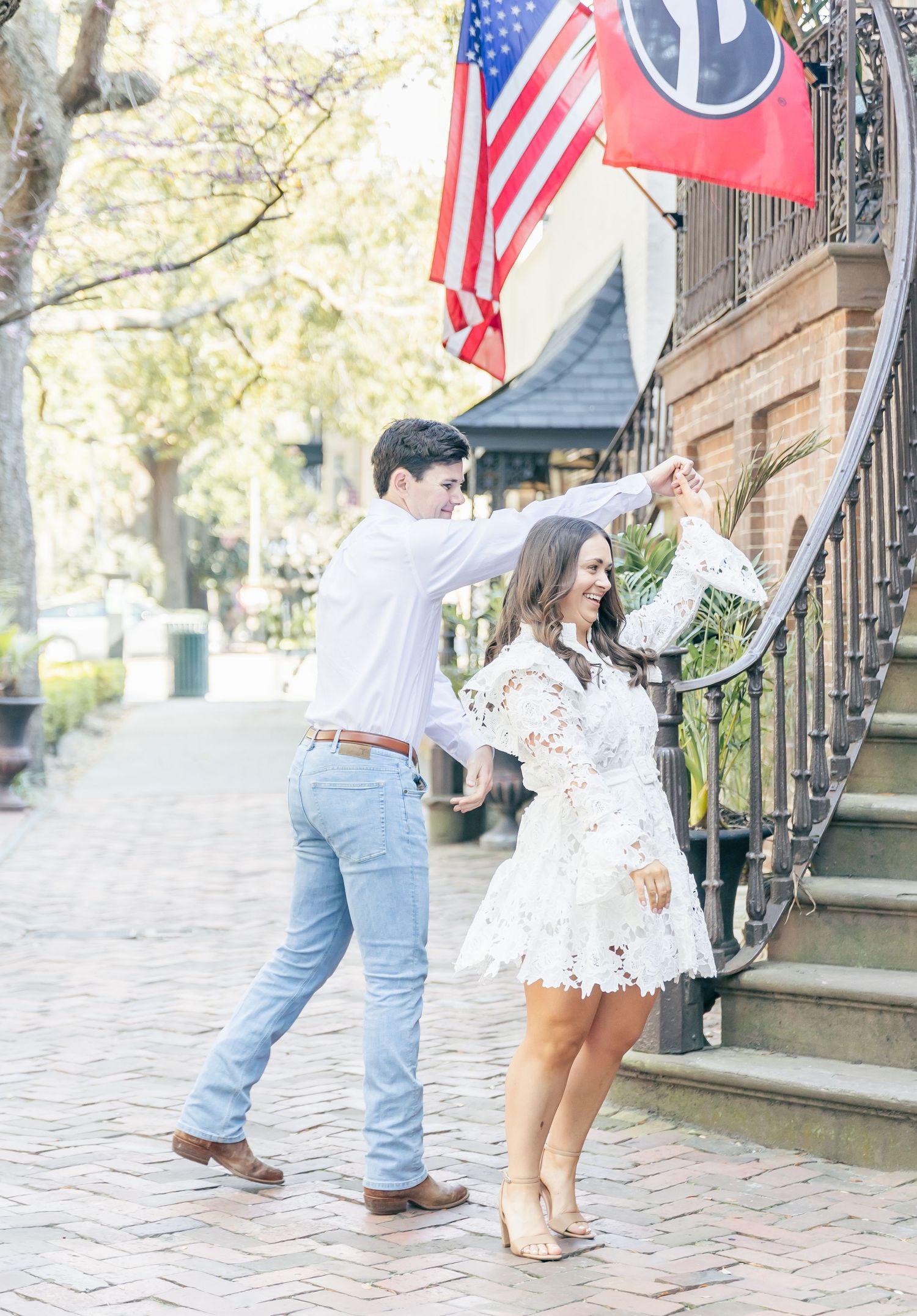 A couple celebrates on historic brick steps under American and Tennessee state flags on a bright spring day.