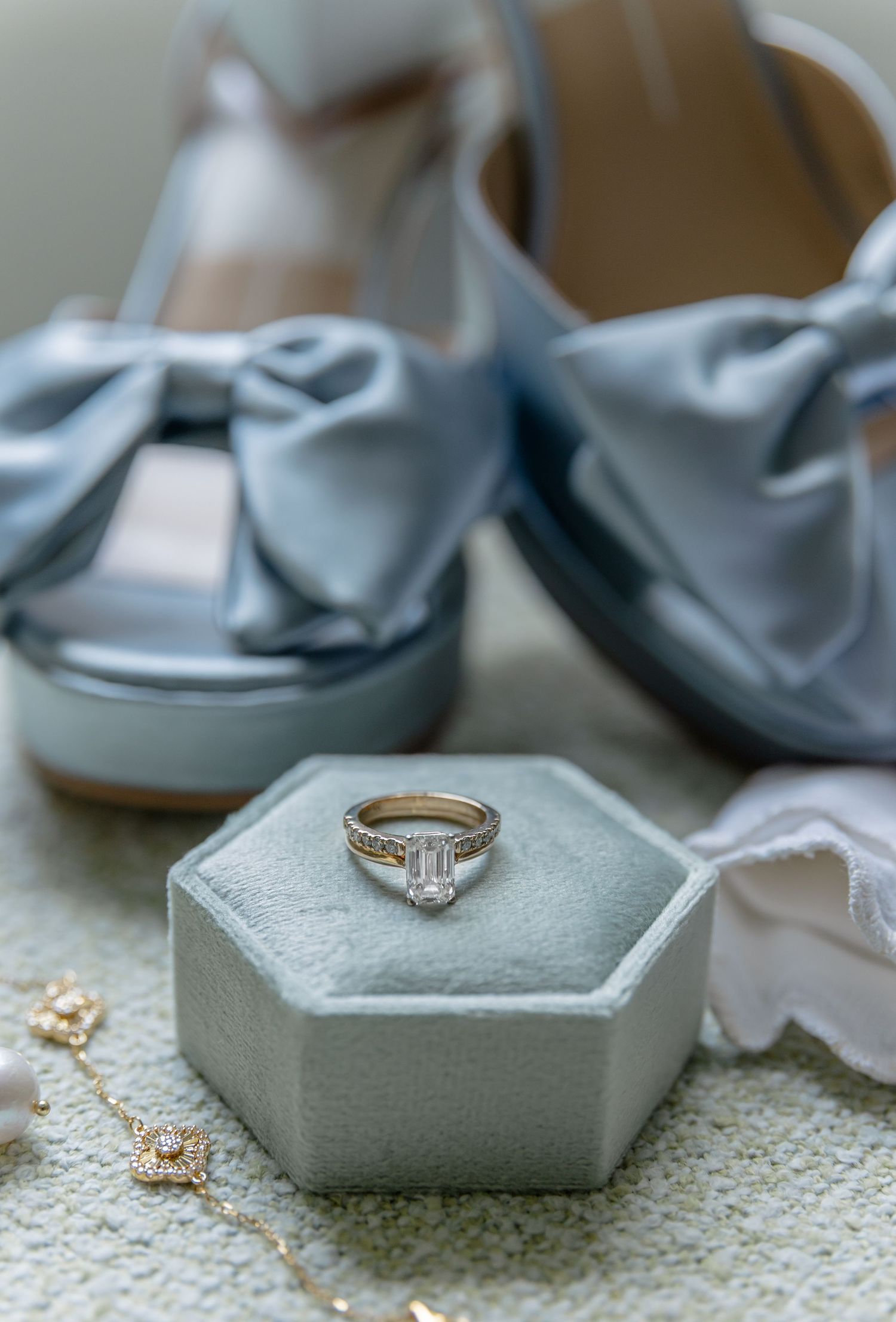 Diamond engagement ring displayed on gray hexagonal ring boxes with soft styling elements.